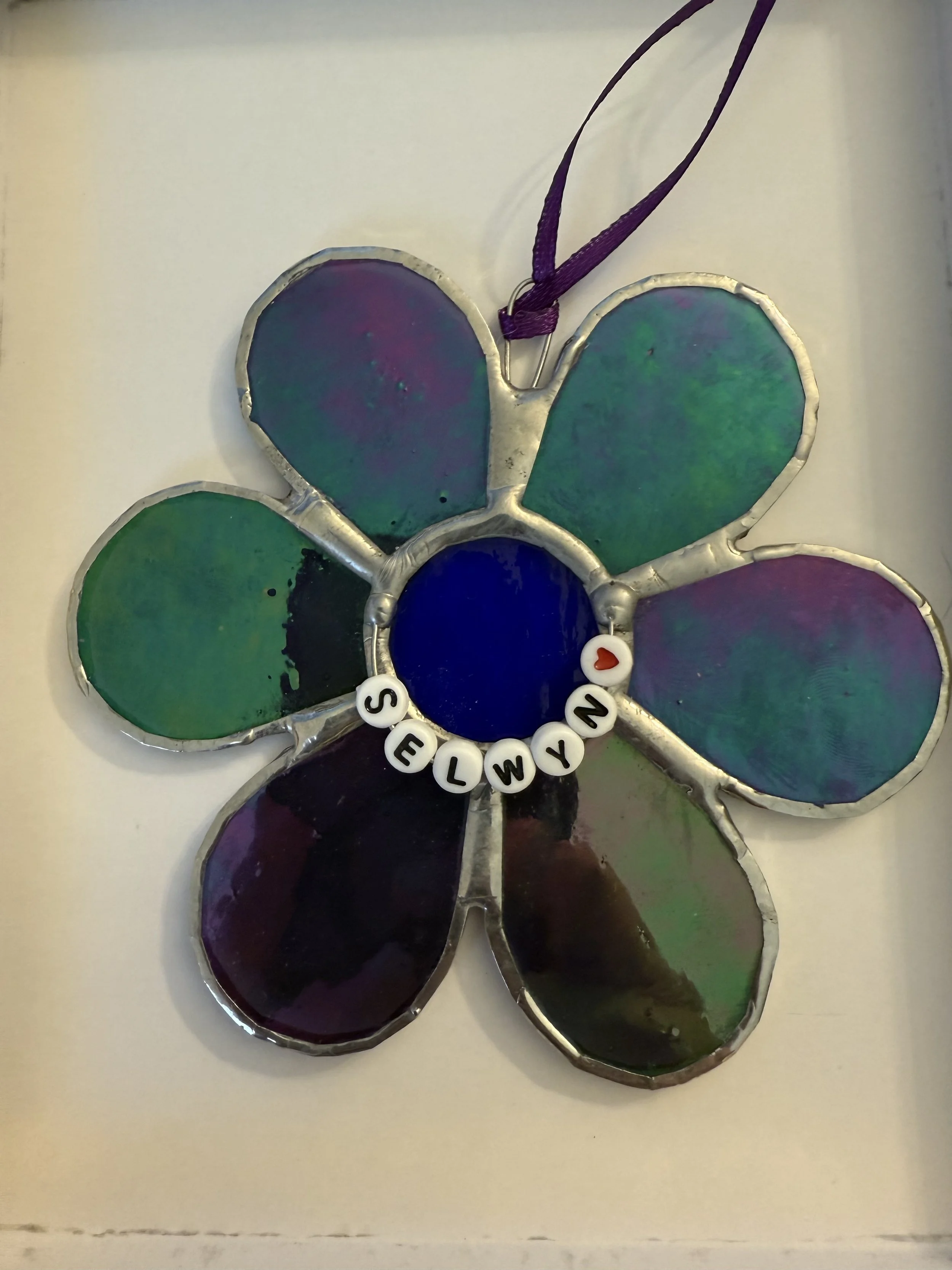 A stained glass flower with a blue center on a white table
