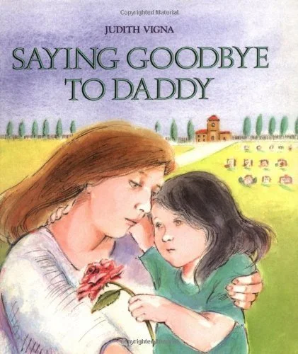 Book cover of "Saying Goodbye to Daddy" by Judith Vigna, depicting a woman with brown hair and a young girl with black hair, sharing a tender moment outdoors with a field, trees, and small buildings in the background.