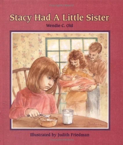 Book cover of 'Stacy Had A Little Sister' by Wendie C. Old, illustrated by Judith Friedman. The cover shows a young girl with red hair sitting at a table, looking sad with a spoon and cereal bowl, while her mother and an older sister are in the backg