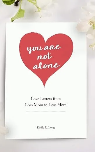 A book cover with a large red heart and the words 'you are not alone' inside it, titled 'Love Letters from Loss Mom to Loss Mom' by Emily R. Long, surrounded by white flowers.