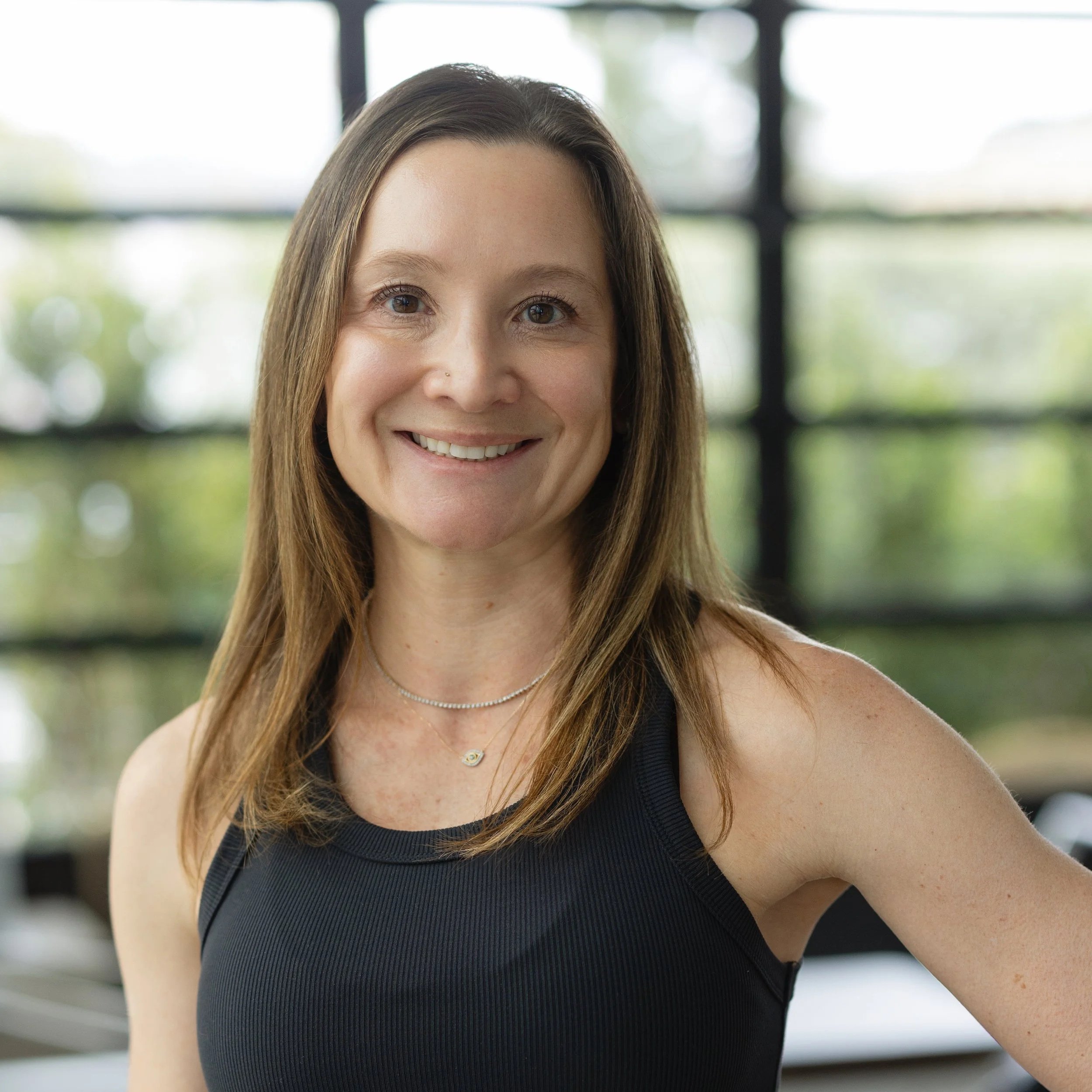 Smiling woman with long blonde hair wearing a black tank top.