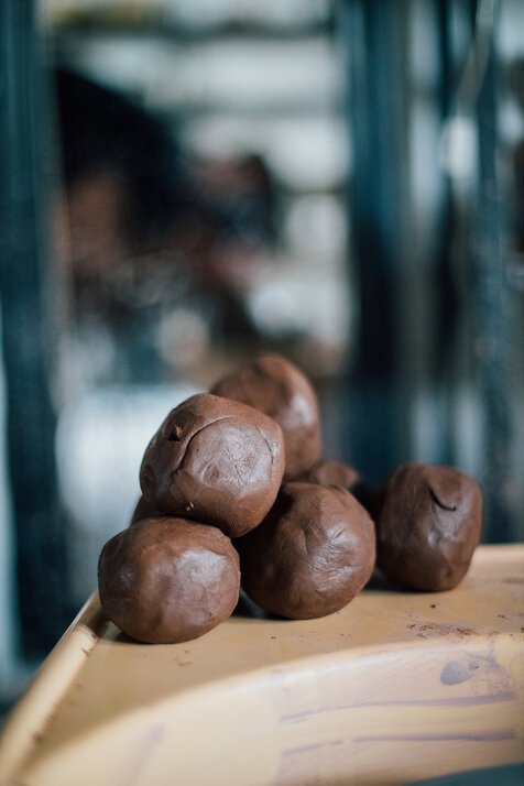 A close-up of several chocolate truffles or bonbons on a wooden or ceramic surface.