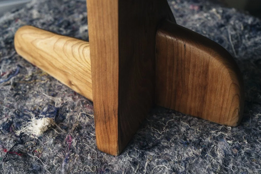 Close-up of a wooden furniture leg art sculpture on a textured carpet.