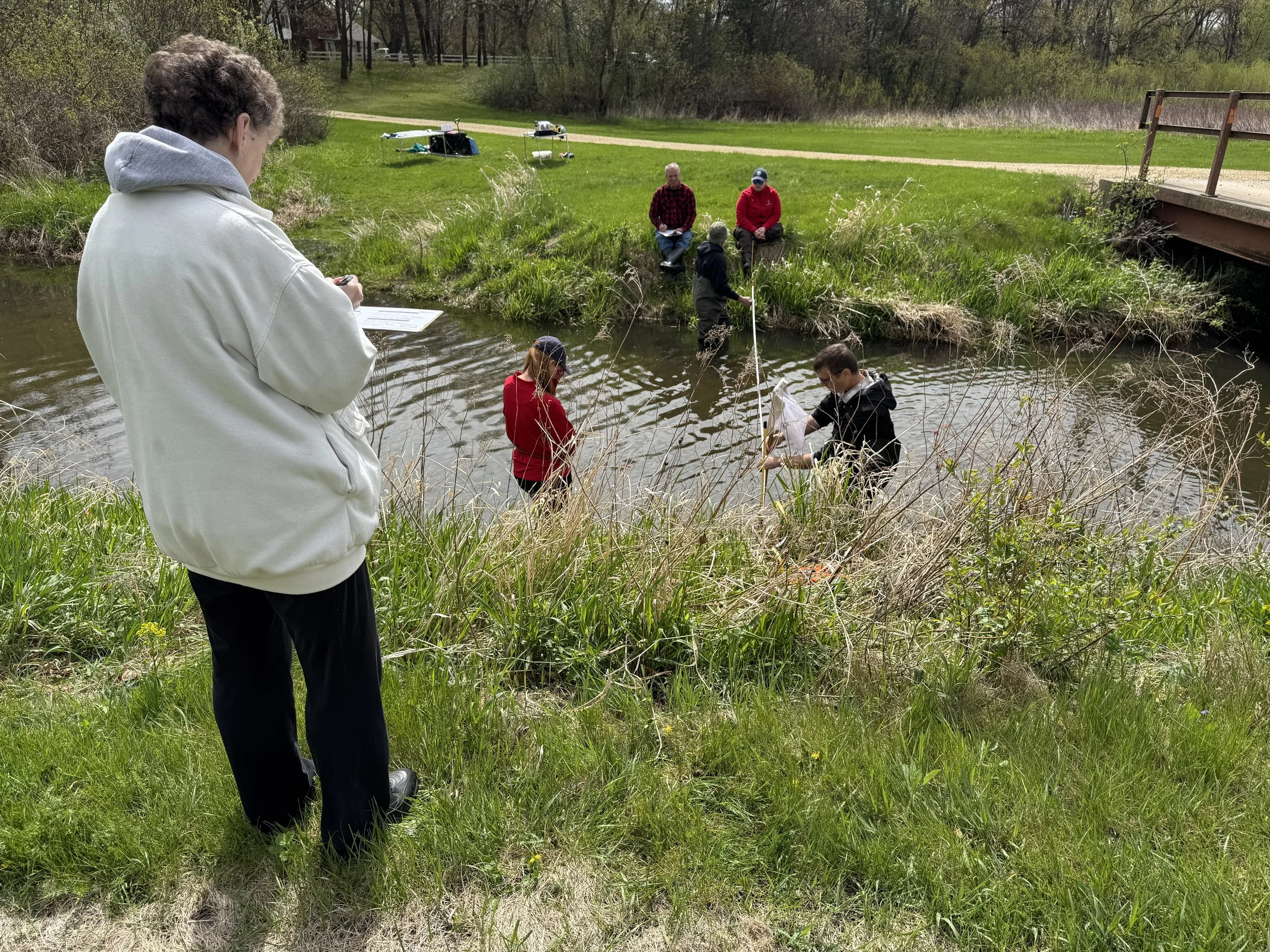 Instruction on measuring and calculating stream flow; shown is Craig Ellefson measuring stream depth intervals at a stream cross section to calculate cross sectional area in the equation.
