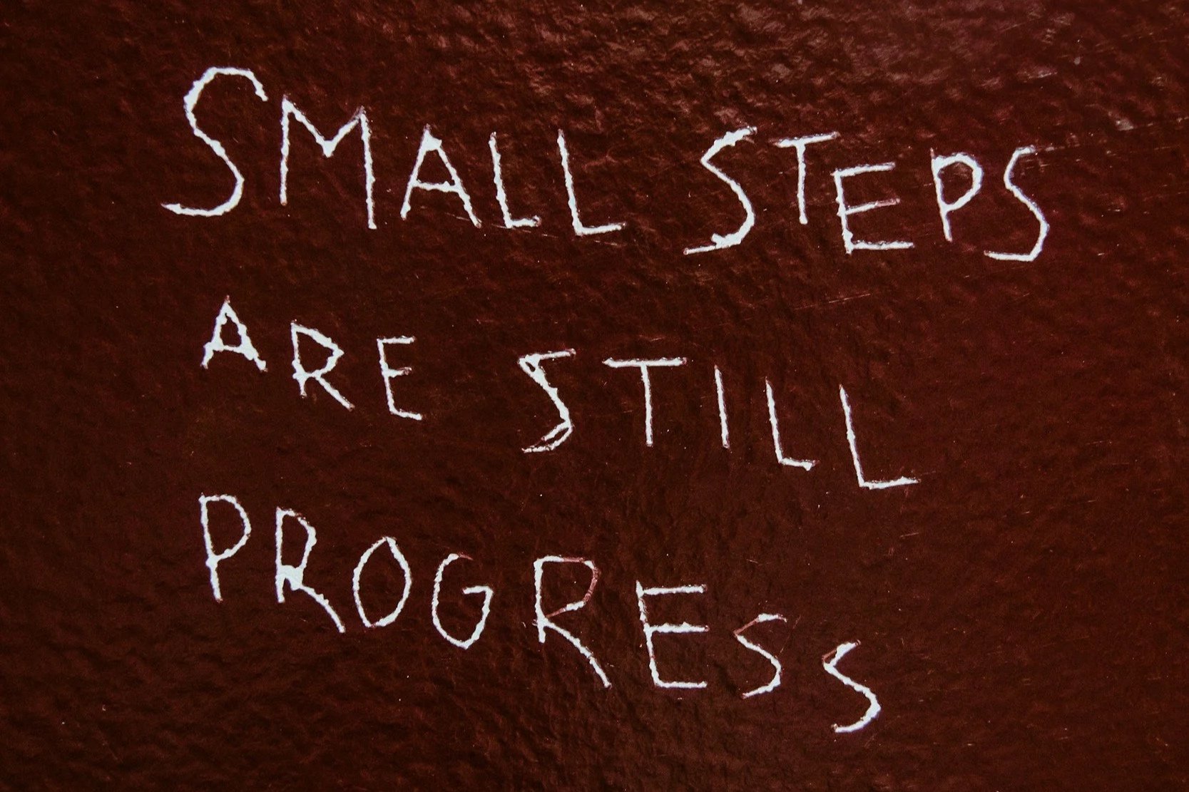 words written on a chalk board that read small steps are still progress