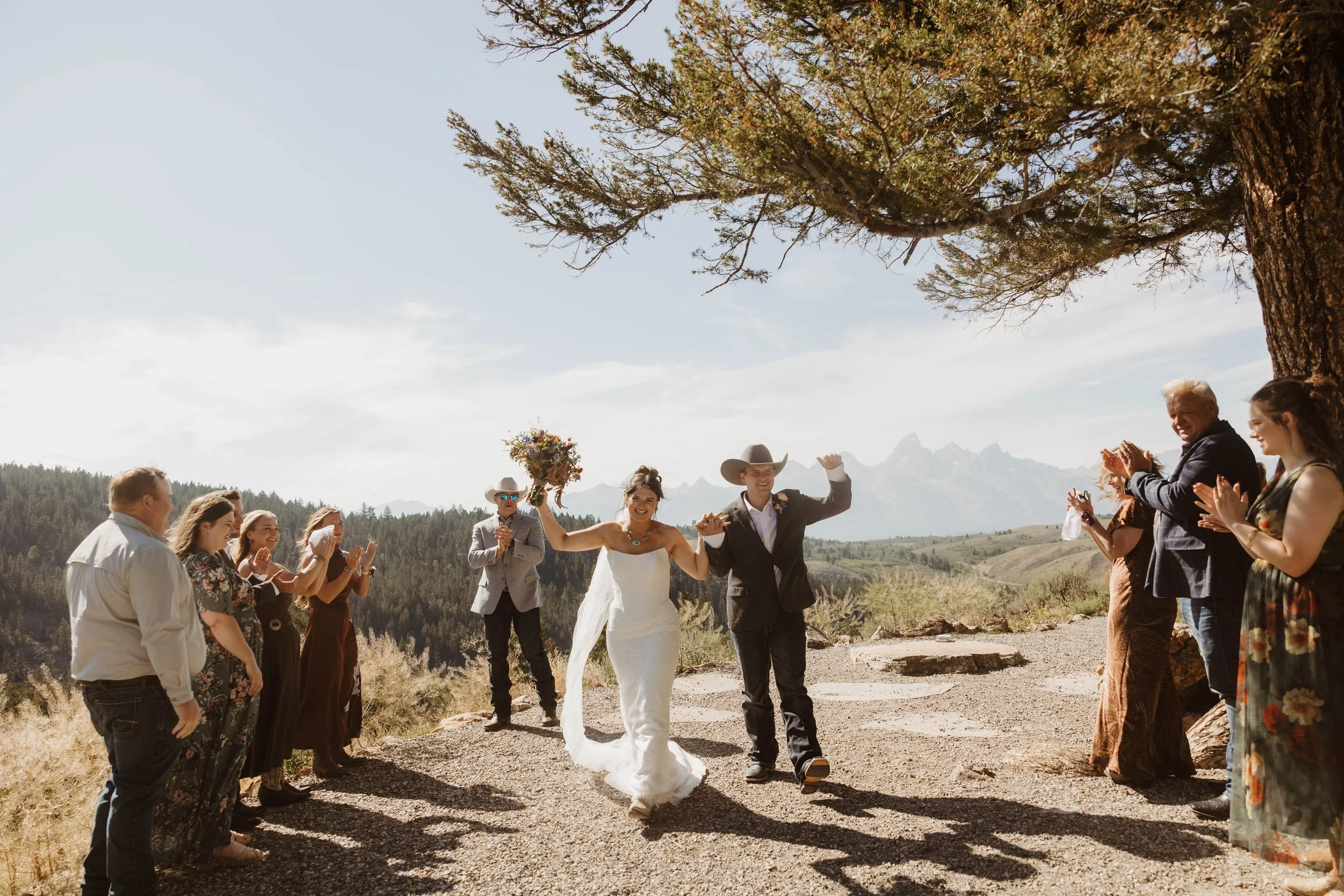 A Montana bride and groom sharing a kiss in a natural outdoor setting with mountains and trees in the background, dressed in wedding attire.