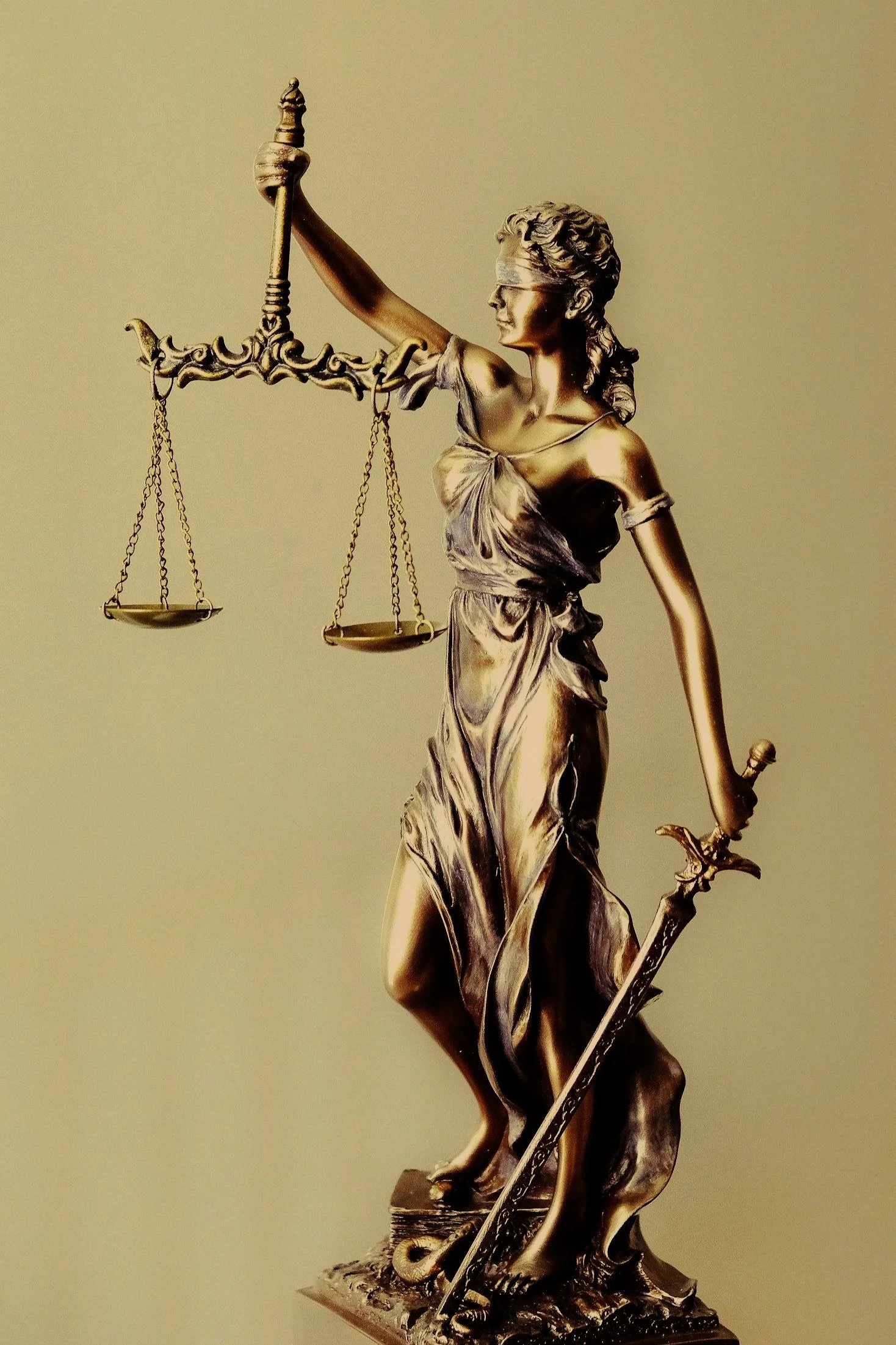 Bronze statue of Lady Justice holding scales in her left hand and a sword in her right hand. She is blindfolded and stands on a decorative base.