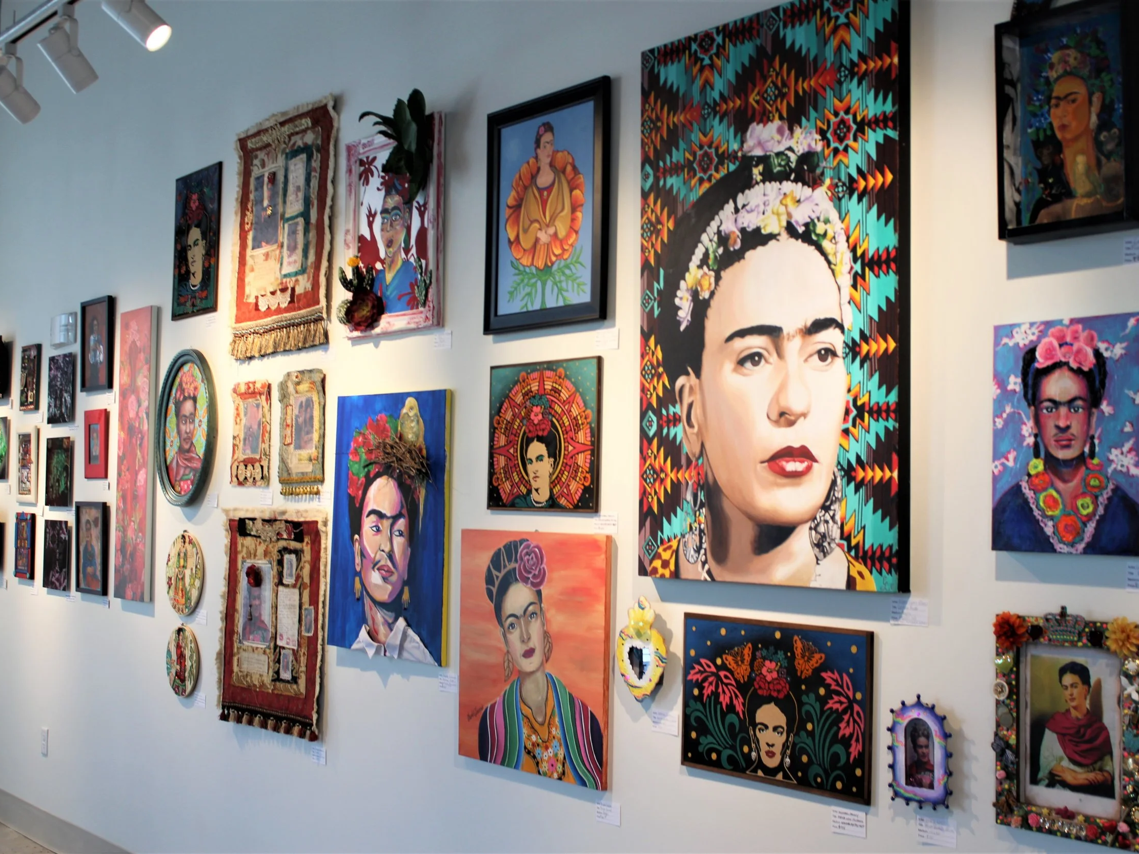 Gallery wall with colorful portraits of Frida Kahlo and other artwork, including paintings and decorative pieces. Westwood - Morrison Road, Denver, CO