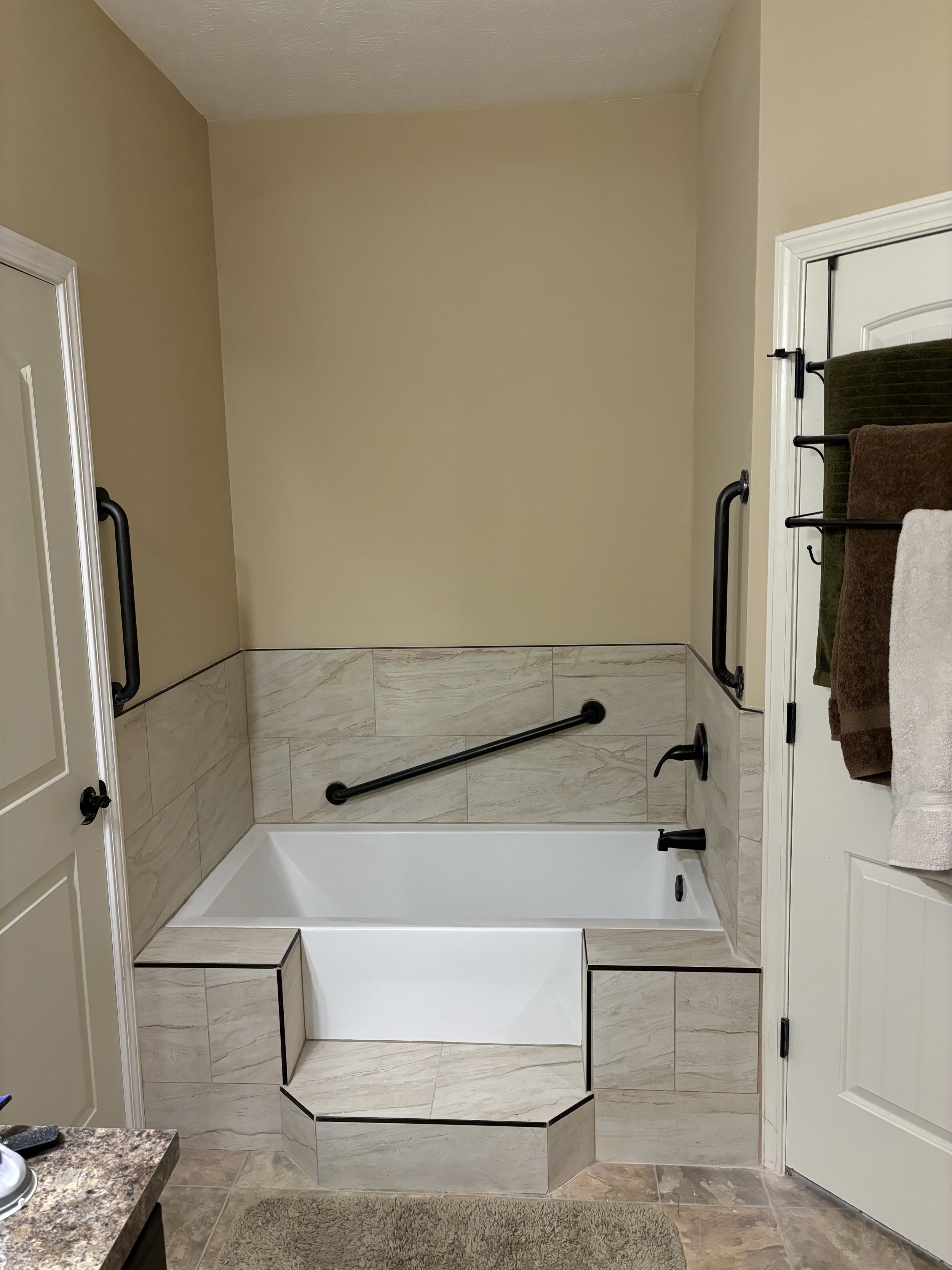 Grab bars installed on low-entry bathtub steps and inside the tub for added safety and support.