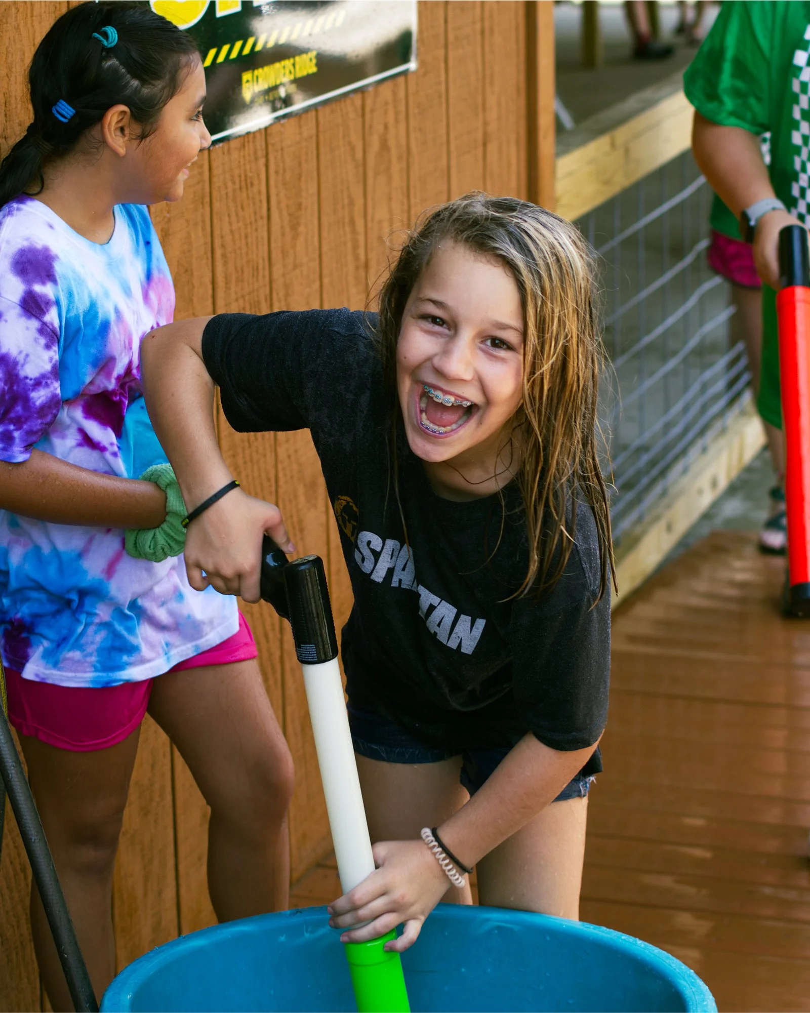 an excited girl fills her super soaker gun with water on a hot summer day