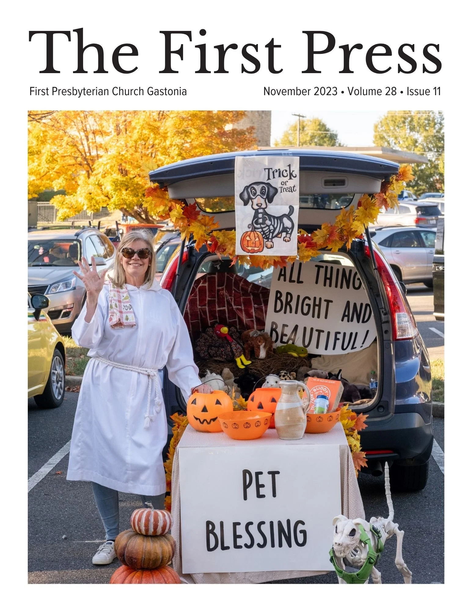a blonde woman waves at the camera in front or her car for trunk or treat