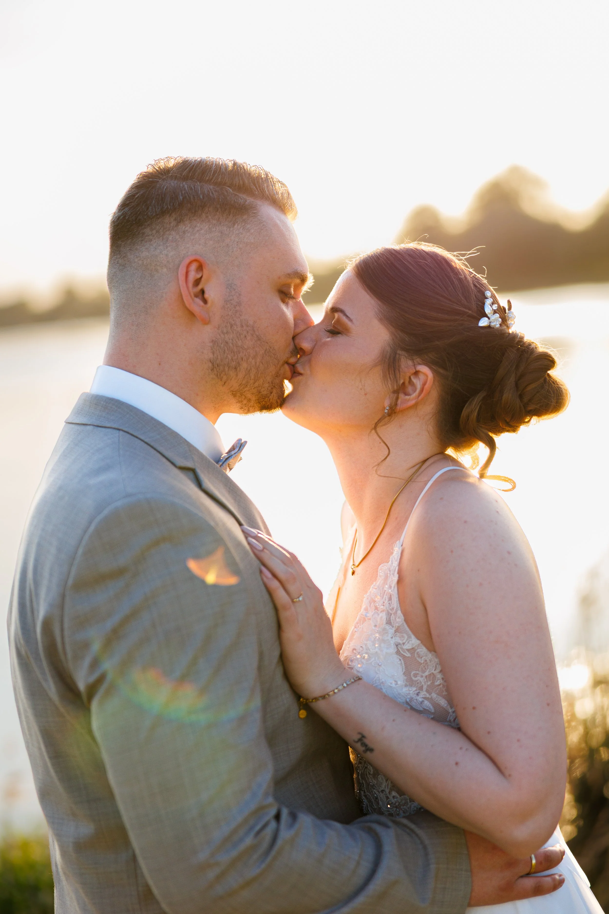 Ein Brautpaar bei einer Hochzeit im Sonnenuntergang, das sich küsst