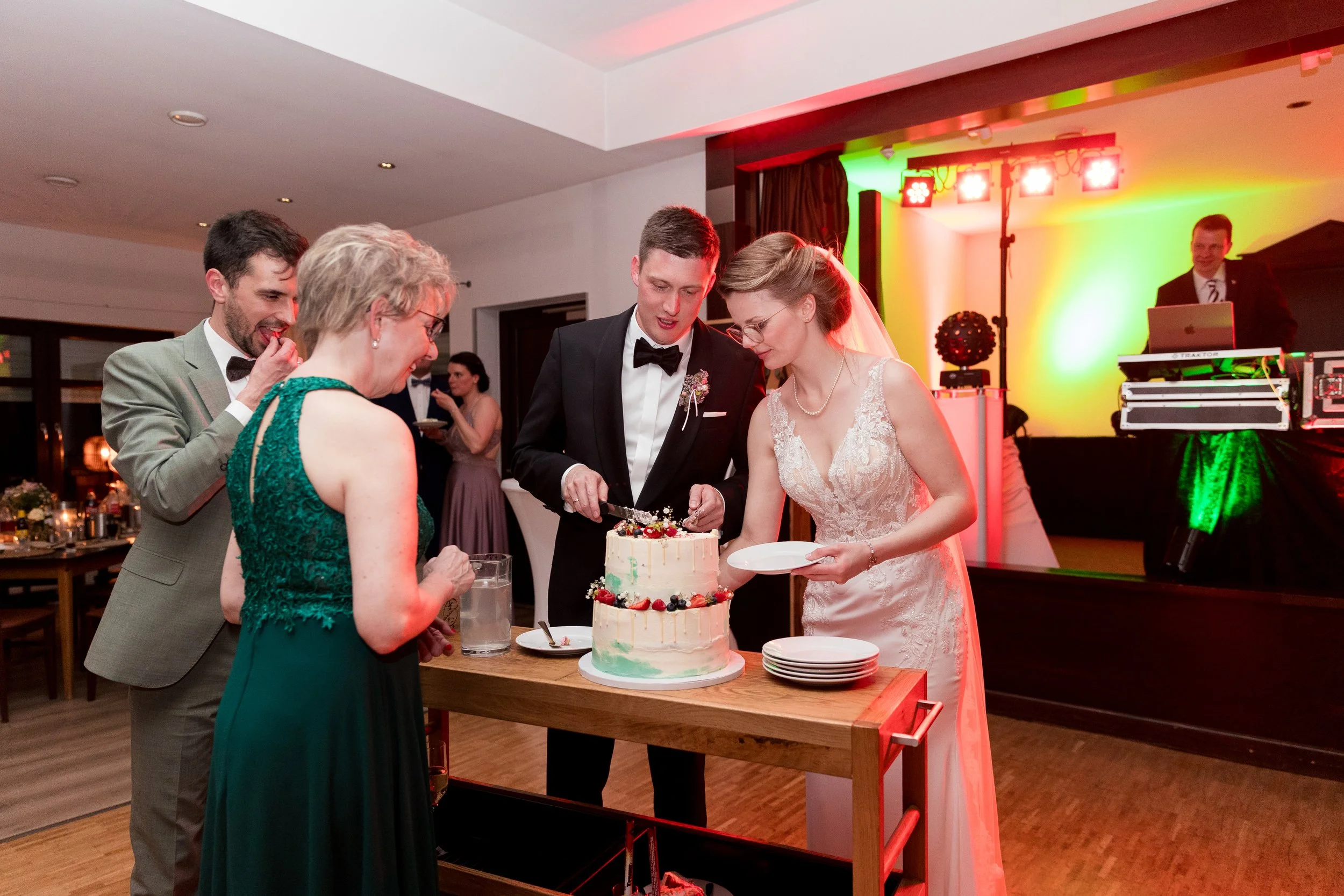 Hochzeitspaar schneidet Hochzeitstorte auf einer Feier.