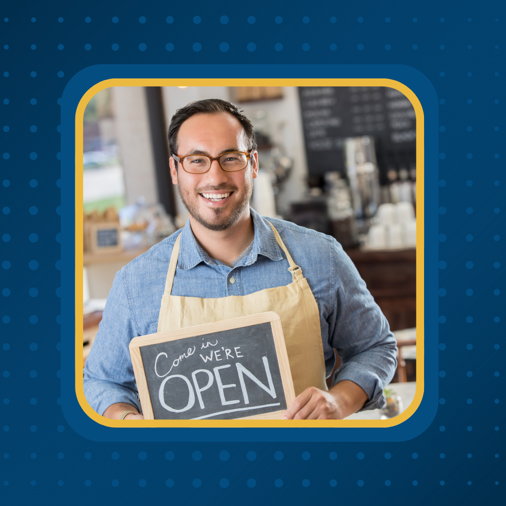 Smiling small business owner in an apron holding a Come In We're Open sign