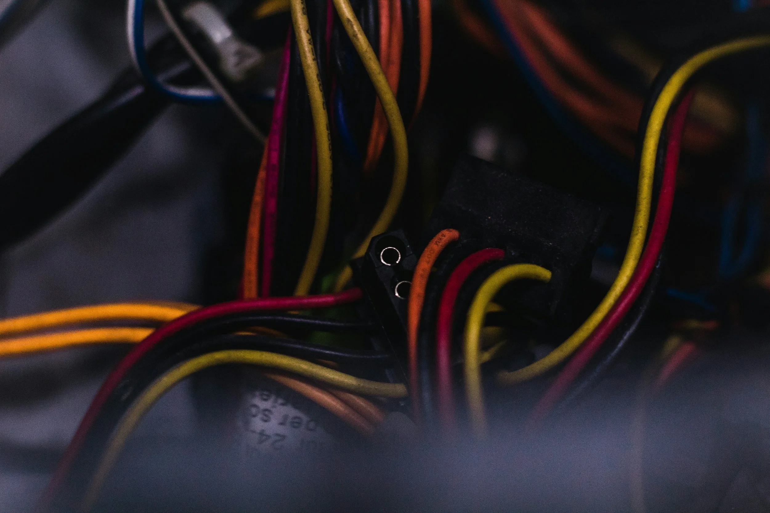 Close-up of tangled multicolored wires and connectors inside a computer or electronic device.