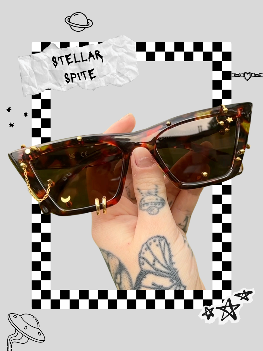A person holding a pair of tortoiseshell sunglasses with gold embellishments and chain, surrounded by space-themed doodles on a gray background.