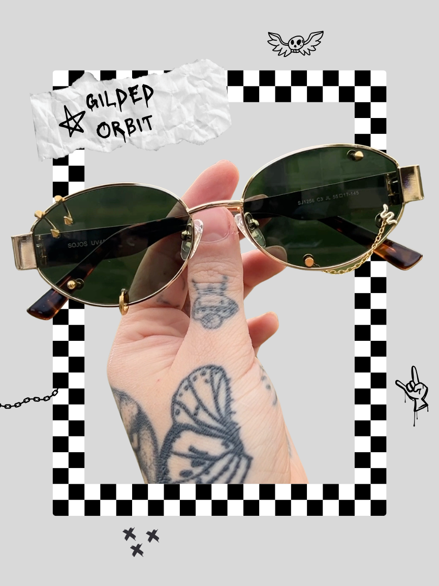 A hand with tattoos holding a pair of oval sunglasses with dark lenses and gold frames. The background features a checkered border, a crumpled paper with 'GILDED ORBIT' written on it, and various doodles including a flying skull with wings, a hand with a raised index finger, a chain, and several small crosses.