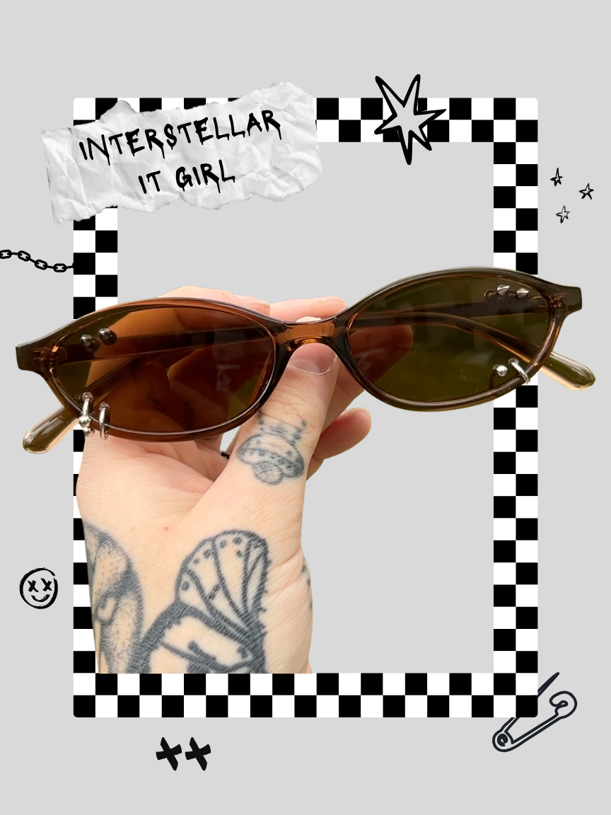 A hand with tattoos holding a pair of brown oval sunglasses against a graphic background with comic-style drawings and text that reads 'Interstellar IT Girl'.