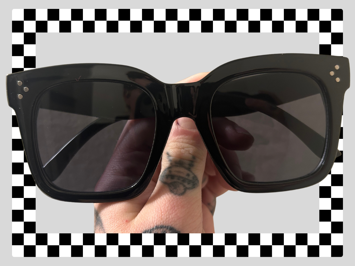 Person holding black sunglasses with a checkered border