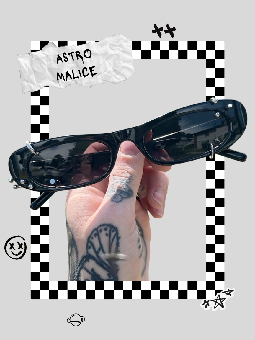 Person holding up black sunglasses with a tattooed hand, outdoors with a cloudy sky reflected in the lenses, decorative black and white checkered border and sticker overlays, including a smiley face, planets, and stars, with a torn paper label reading 'Astro Malice'.