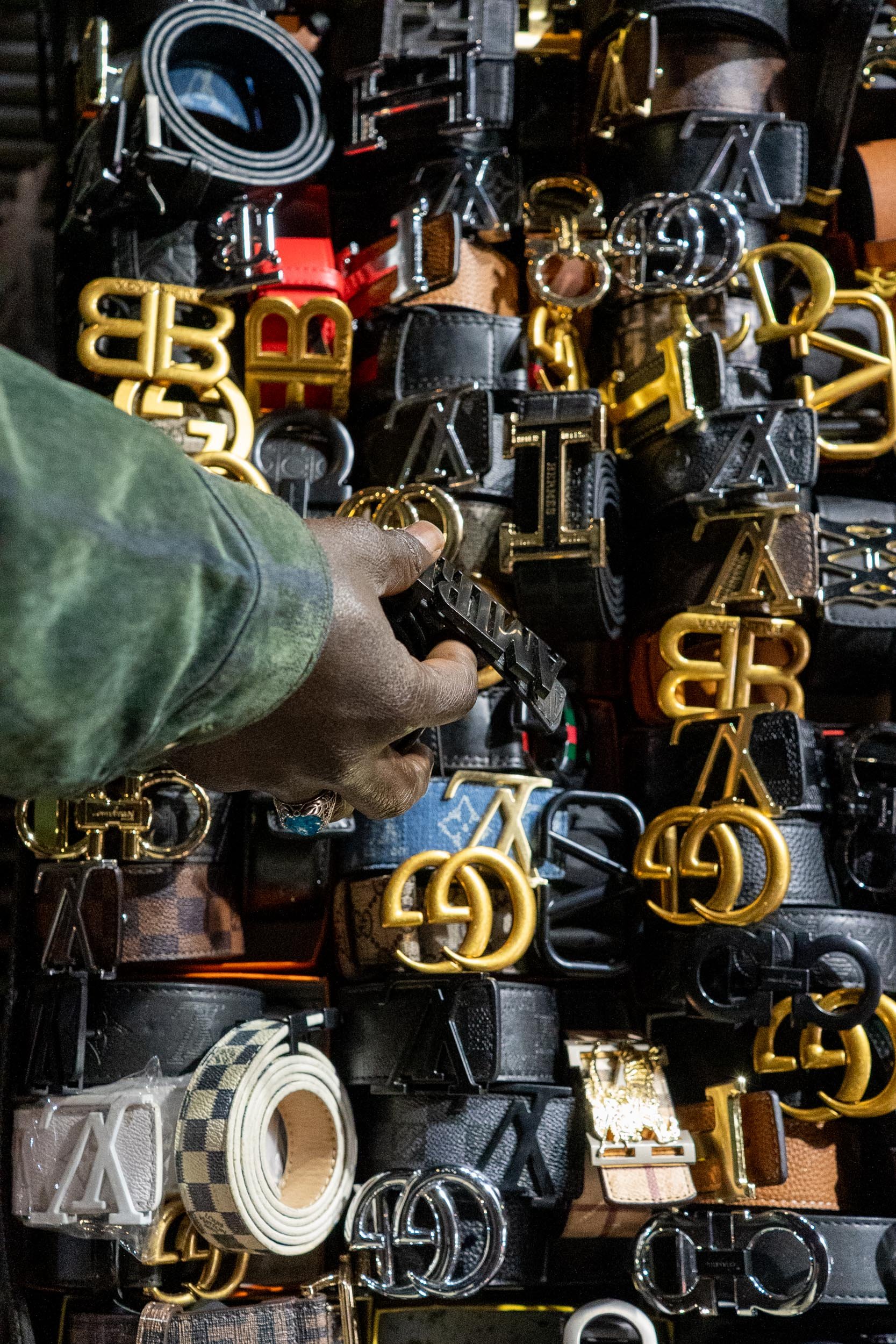 Canal street, New York, March 2026 — A senegalese street vendor arrange merchandise on Canal Street.