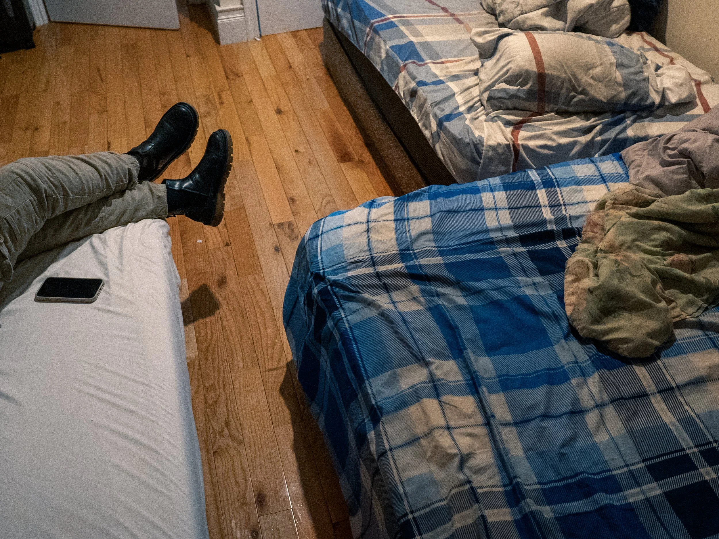 Bronx, New York — Betty rests in the bedroom she shares with three Senegalese men in the Bronx on Tuesday, December 16, 2025. She says she has an issue with men sleeping in the bed next to hers and hopes to move out once she finds stable work.