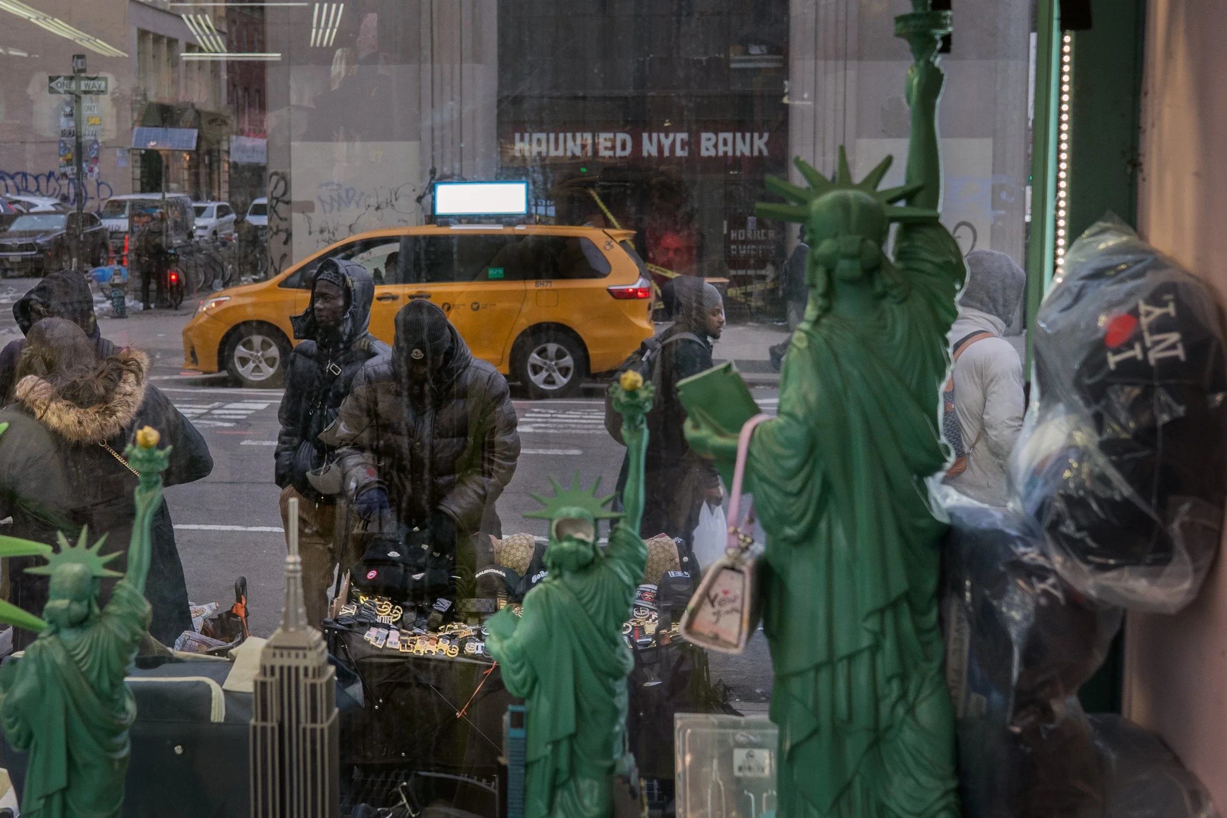 NEW YORK, March 7, 2026 — Senegalese street vendors arrange merchandise for sale in front of a souvenir shop on Canal Street.