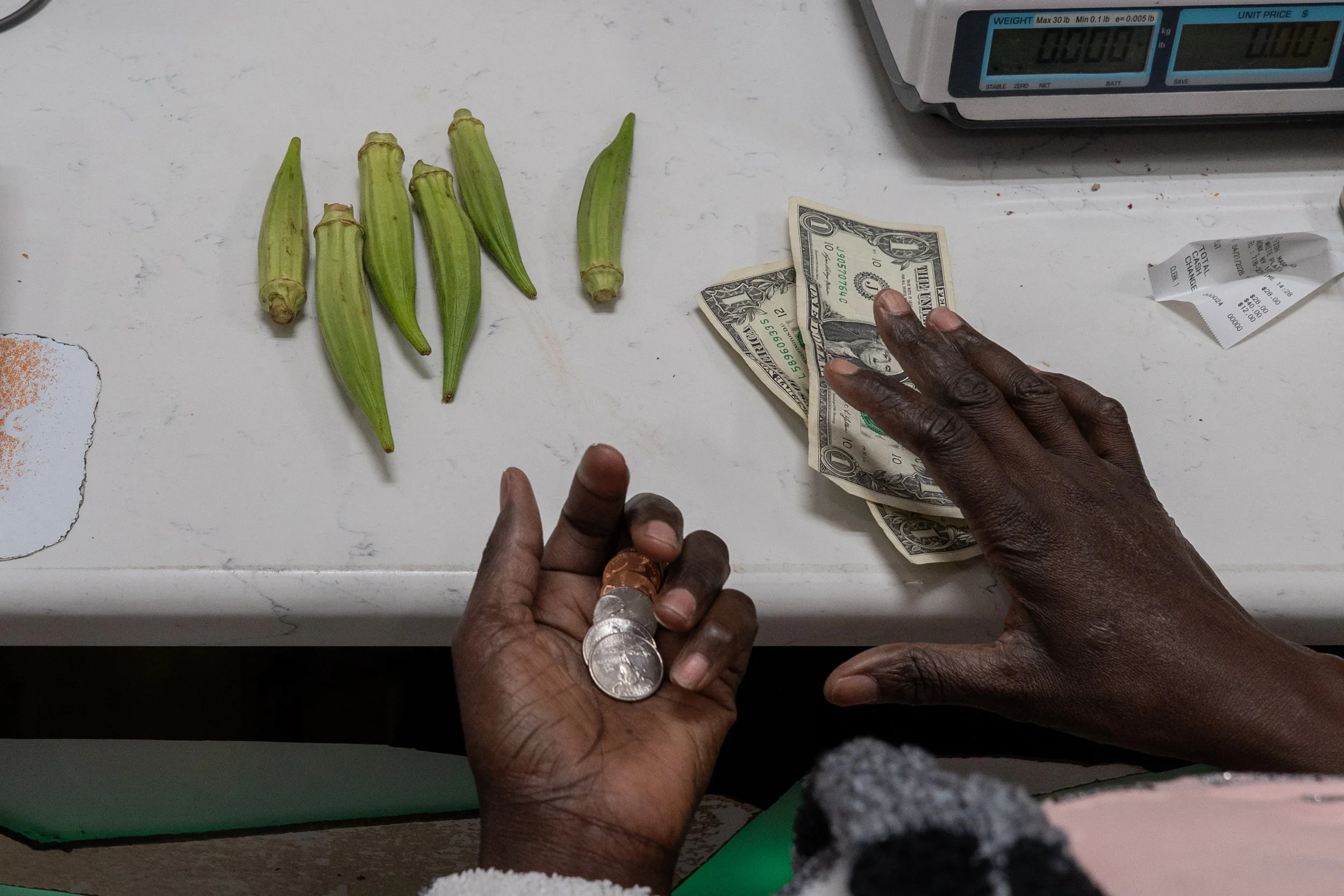 Bronx, New York — Lama, who lives with Khadim and three other Senegalese immigrants, examines how many okra pods she can buy within the day’s food budget in the Bronx on Tuesday, April 21, 2026. 