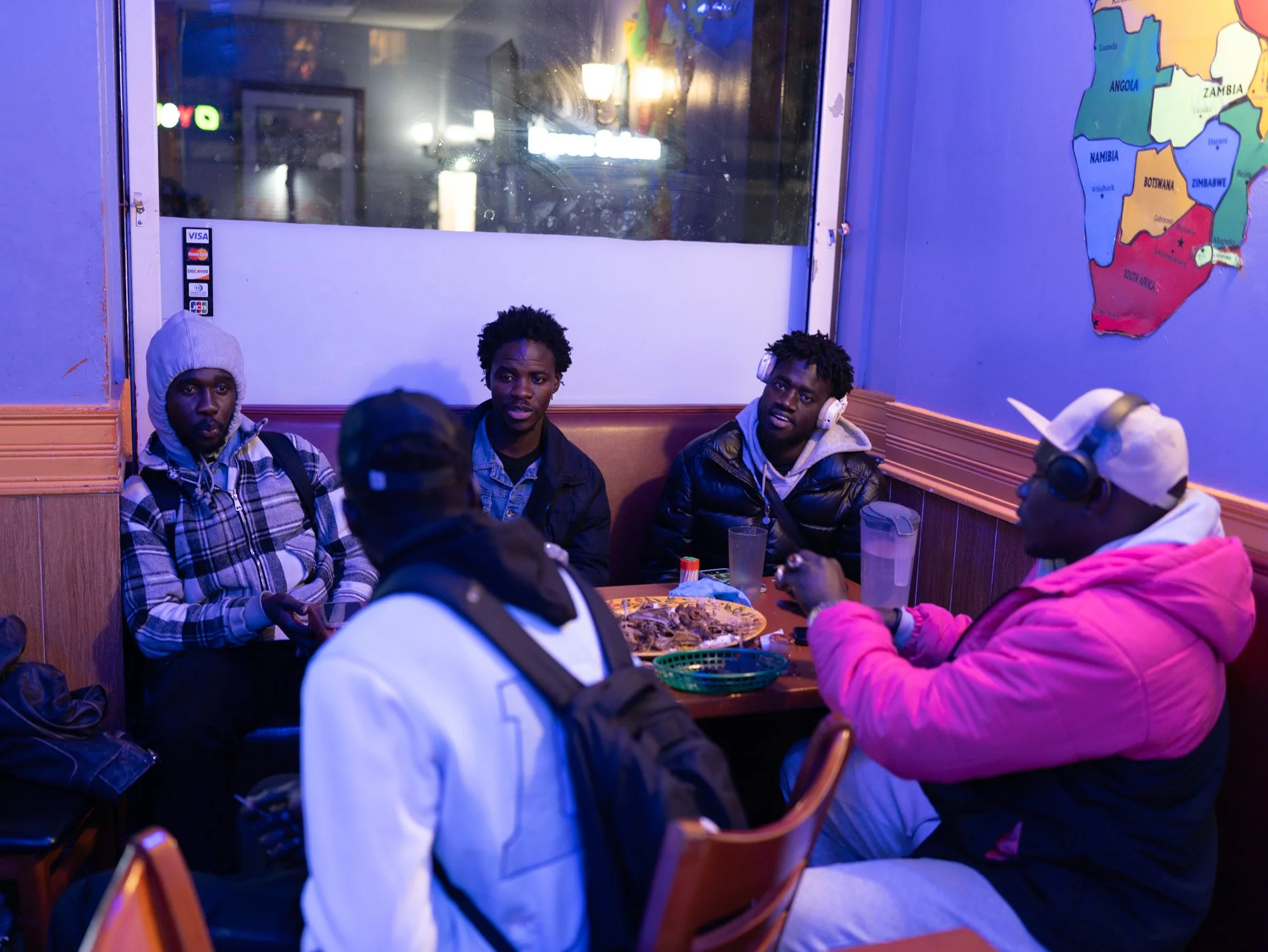 HARLEM, N.Y., October 2024 — Mol and other Senegalese immigrants share a meal before returning to shelters. All are waiting for employment authorization documents while making a living selling goods on the street.