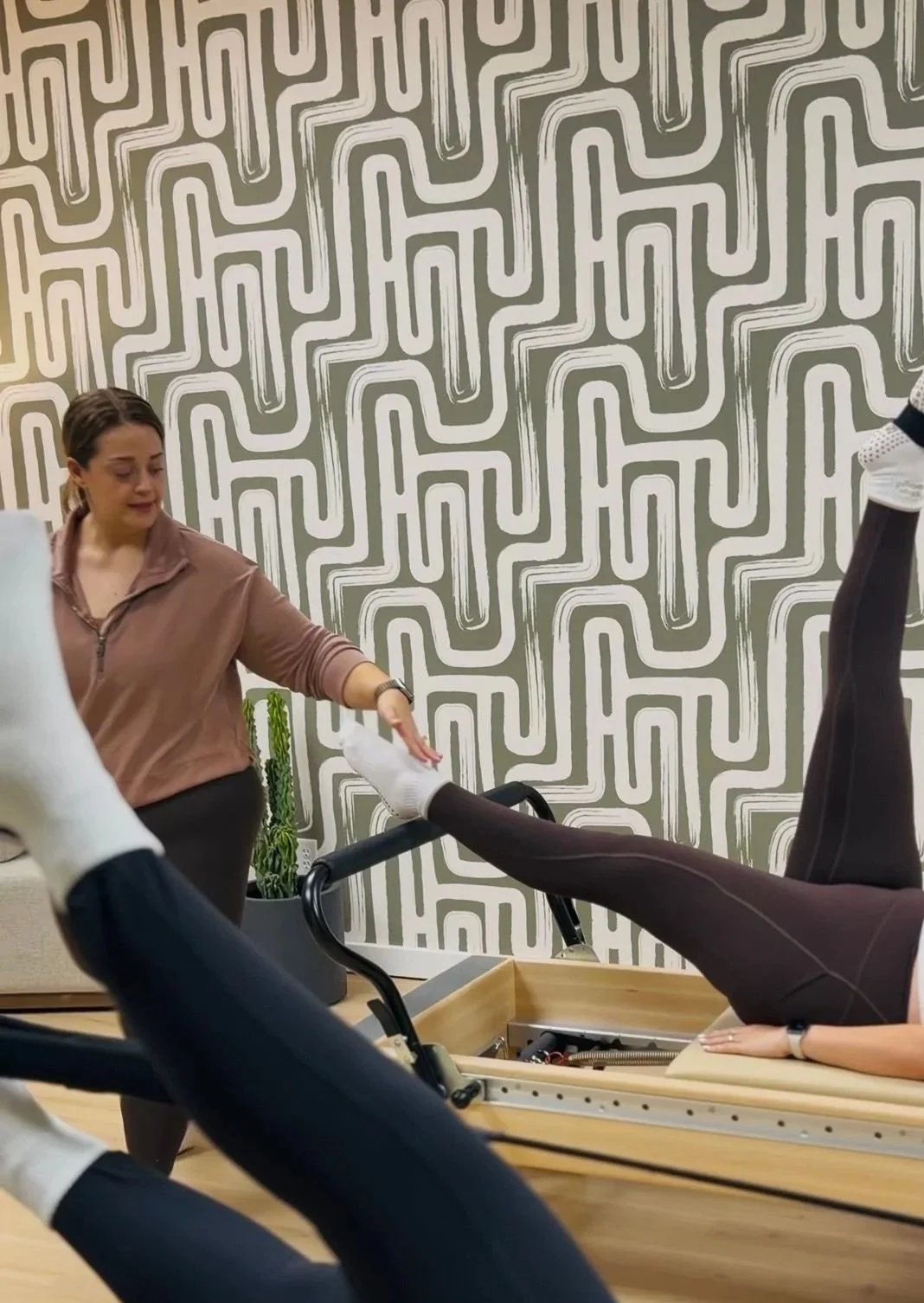 Instructor guiding a man using a Pilates reformer