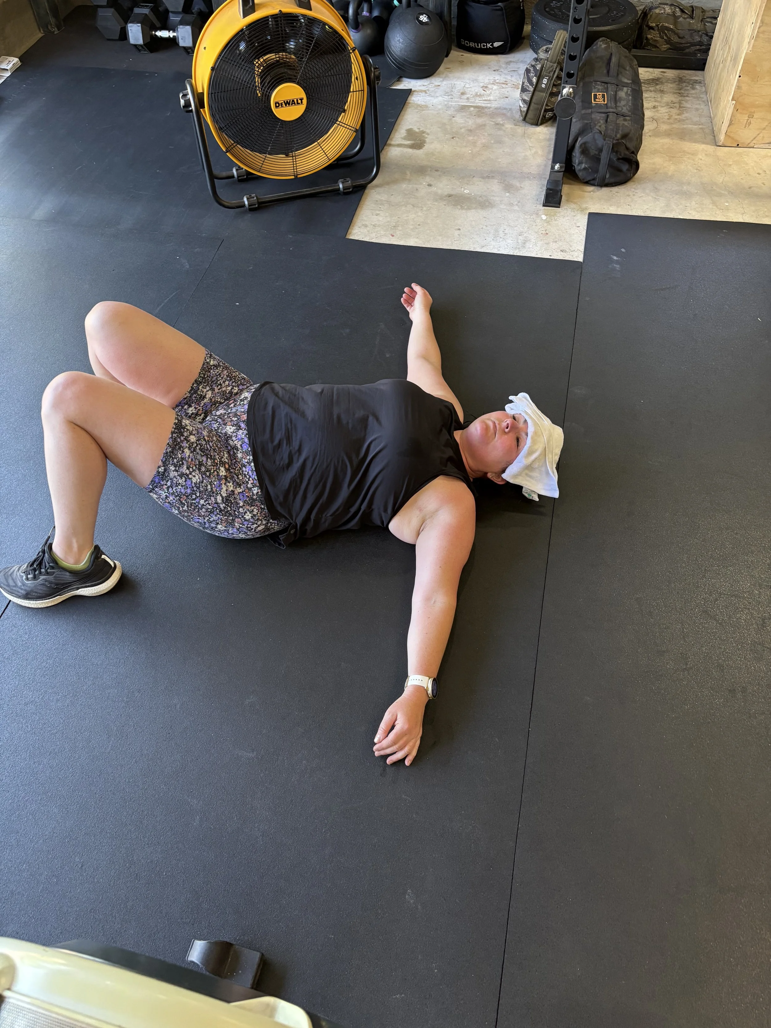 Person lifting barbell in home gym with pink weights and safety pad, wearing athletic clothing.