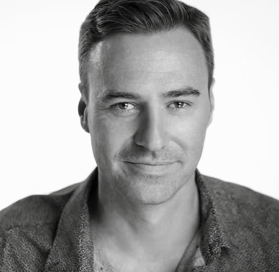 Portrait of a smiling man with short hair in grayscale.