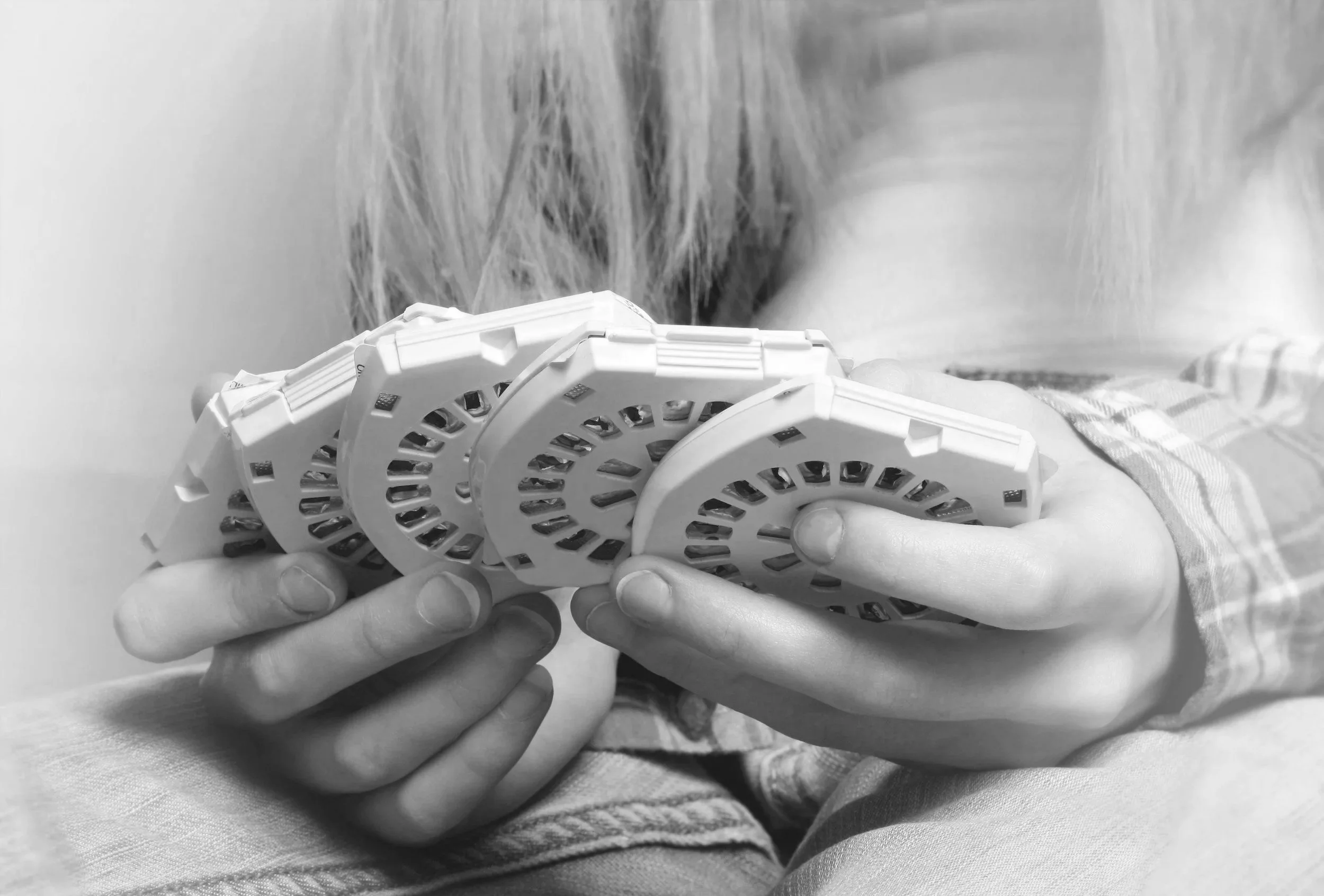 A person holding 4 months' worth of birth control pills, in a fanned-out position, with a woman's partially visible face in the background.