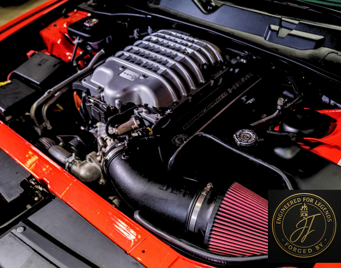Close-up of a red car's engine bay with a supercharged HEMI engine and aftermarket cold air intake, featuring a logo badge in the corner.