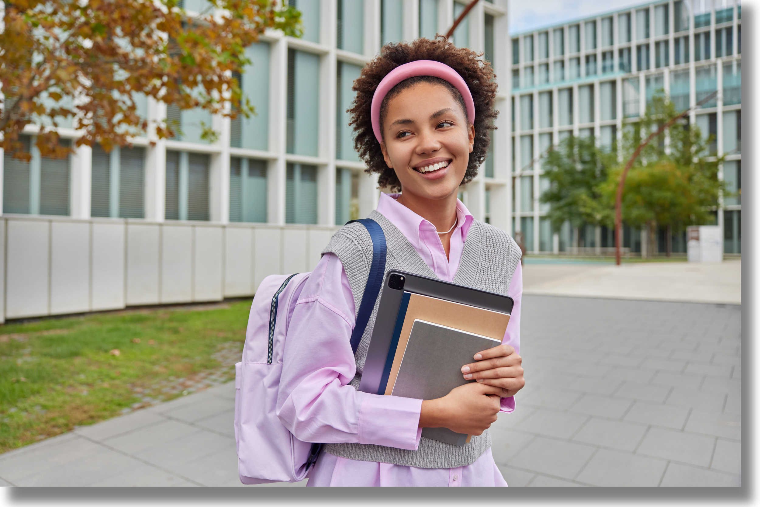 College student standing on campus holding books and a backpack, representing access to campus-based support resources