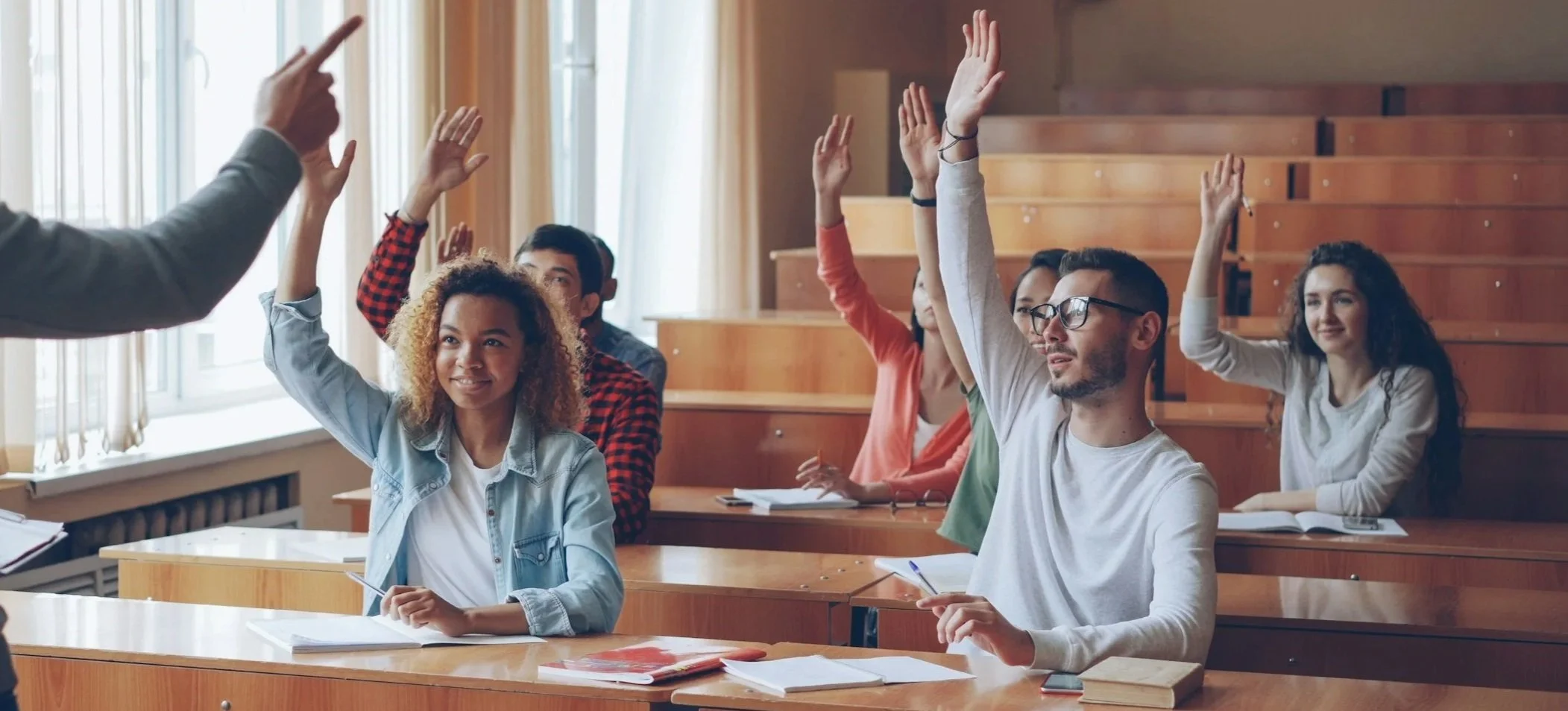 College students raising their hands in a classroom discussion