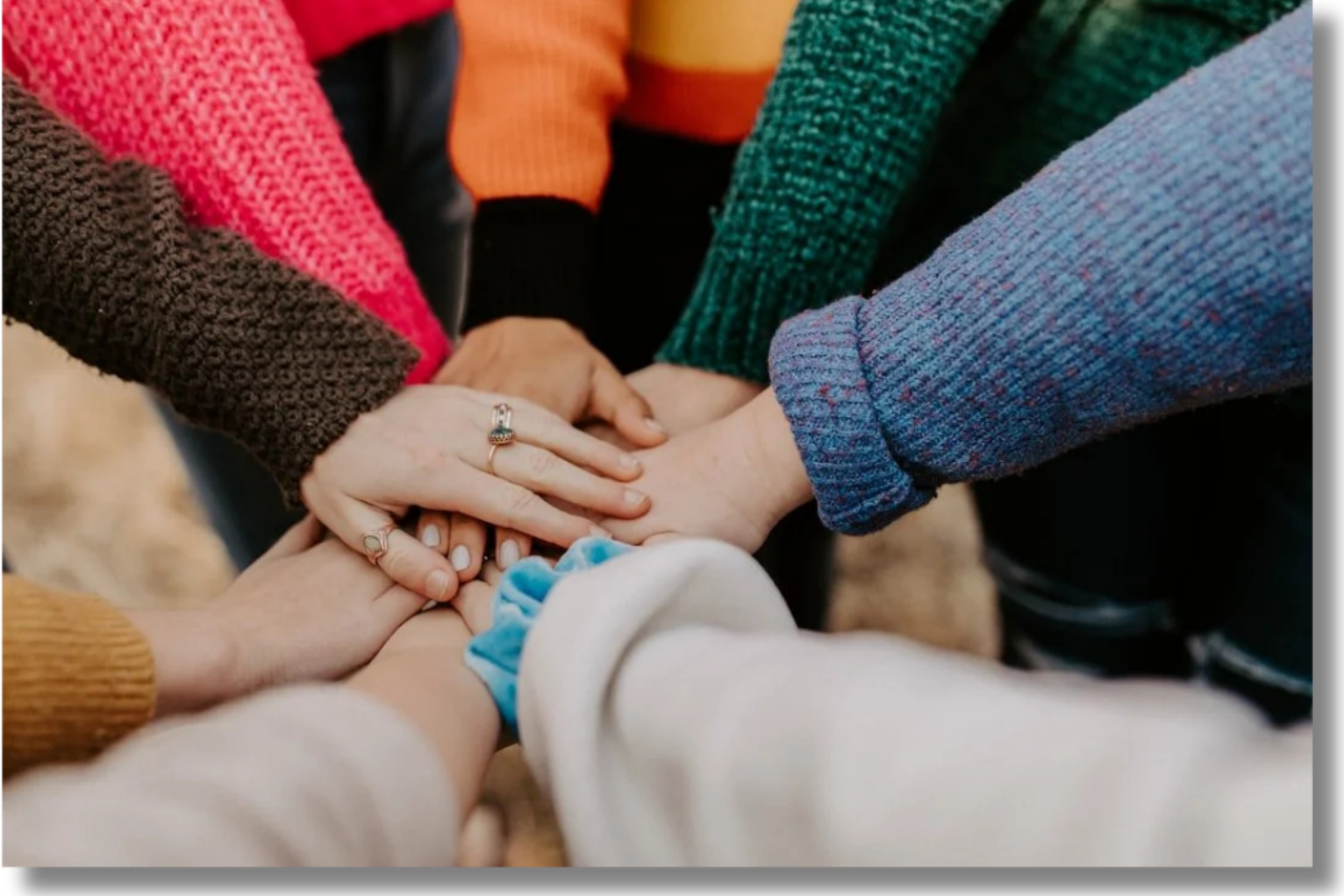 Students placing hands together in a supportive gesture, symbolizing community and campus support services