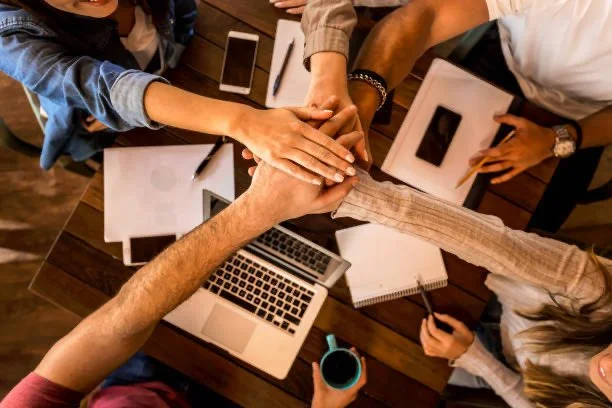 College students placing hands together in a supportive team gesture on campus