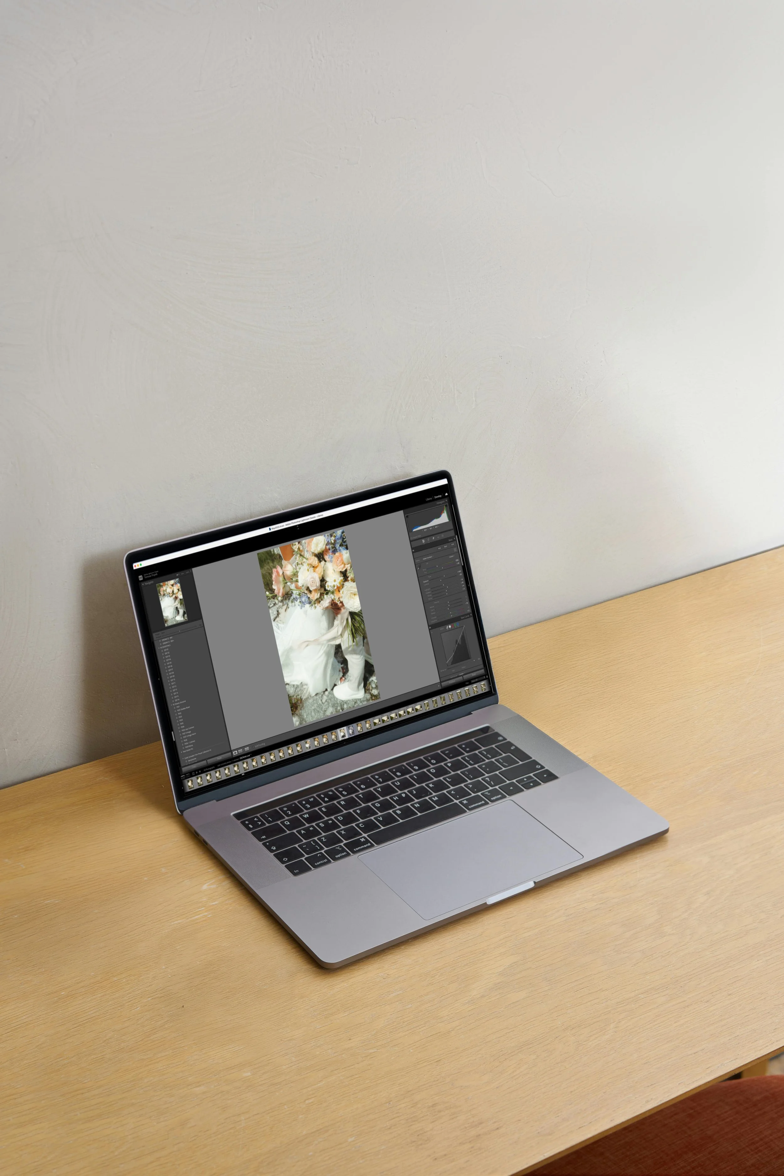 Laptop on a wooden desk displaying a photo editing software with an image of a floral arrangement on screen.