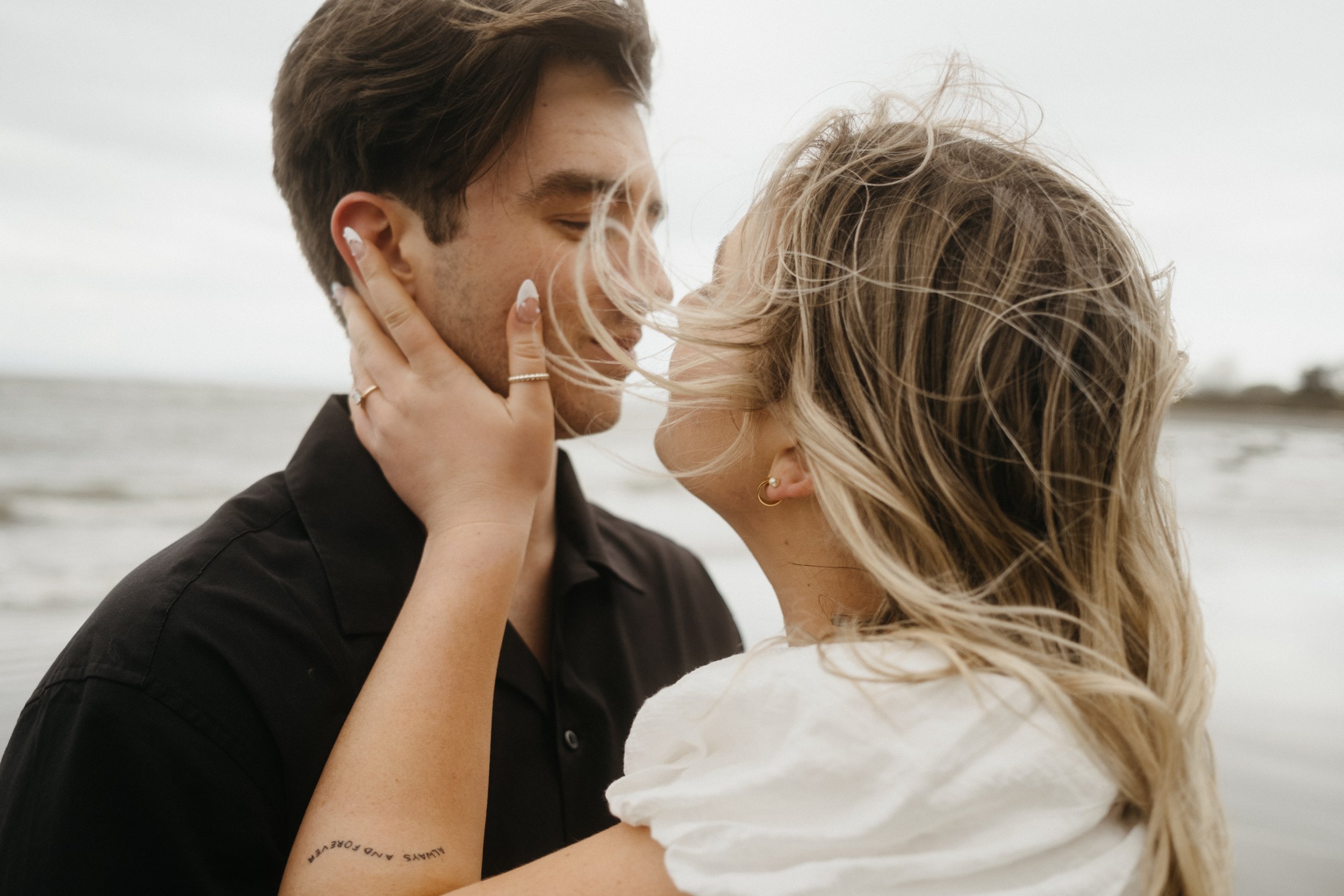 Couple embracing on a windy beach day.