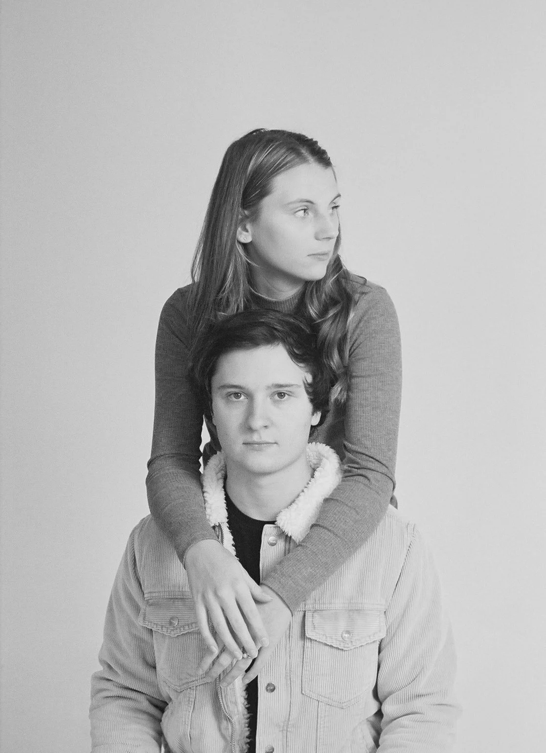 Black and white photo of a woman standing behind a seated man, both looking past the camera.