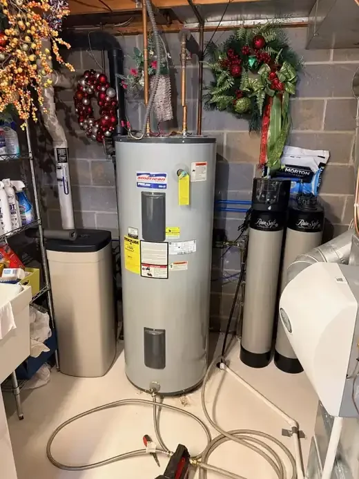 Old American ProLine electric water heater before replacement, being drained