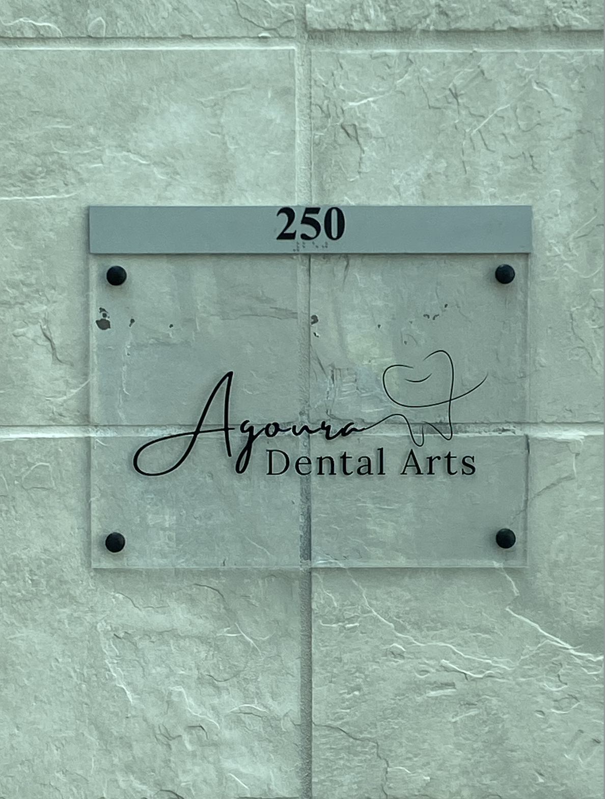 Sign located on a tiled background with the verbiage Agoura Dental Arts 