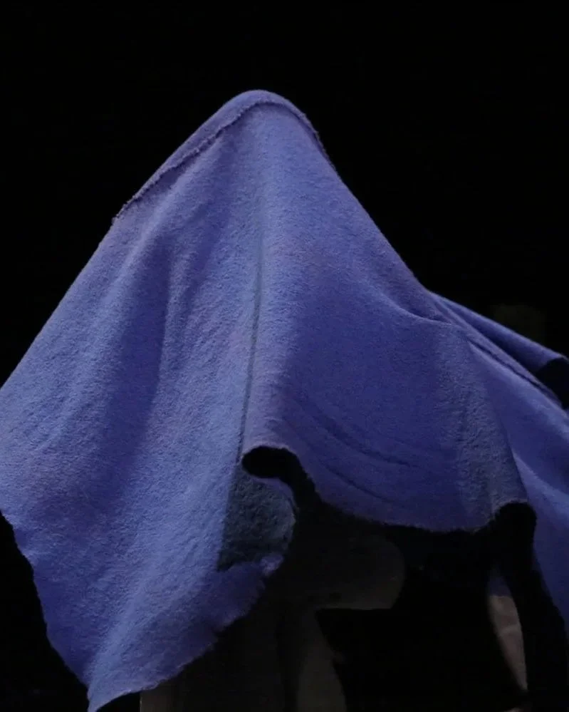 Ghostly, abstract silhouette of a dancer obscured by swirling, deep sky-blue fabric.