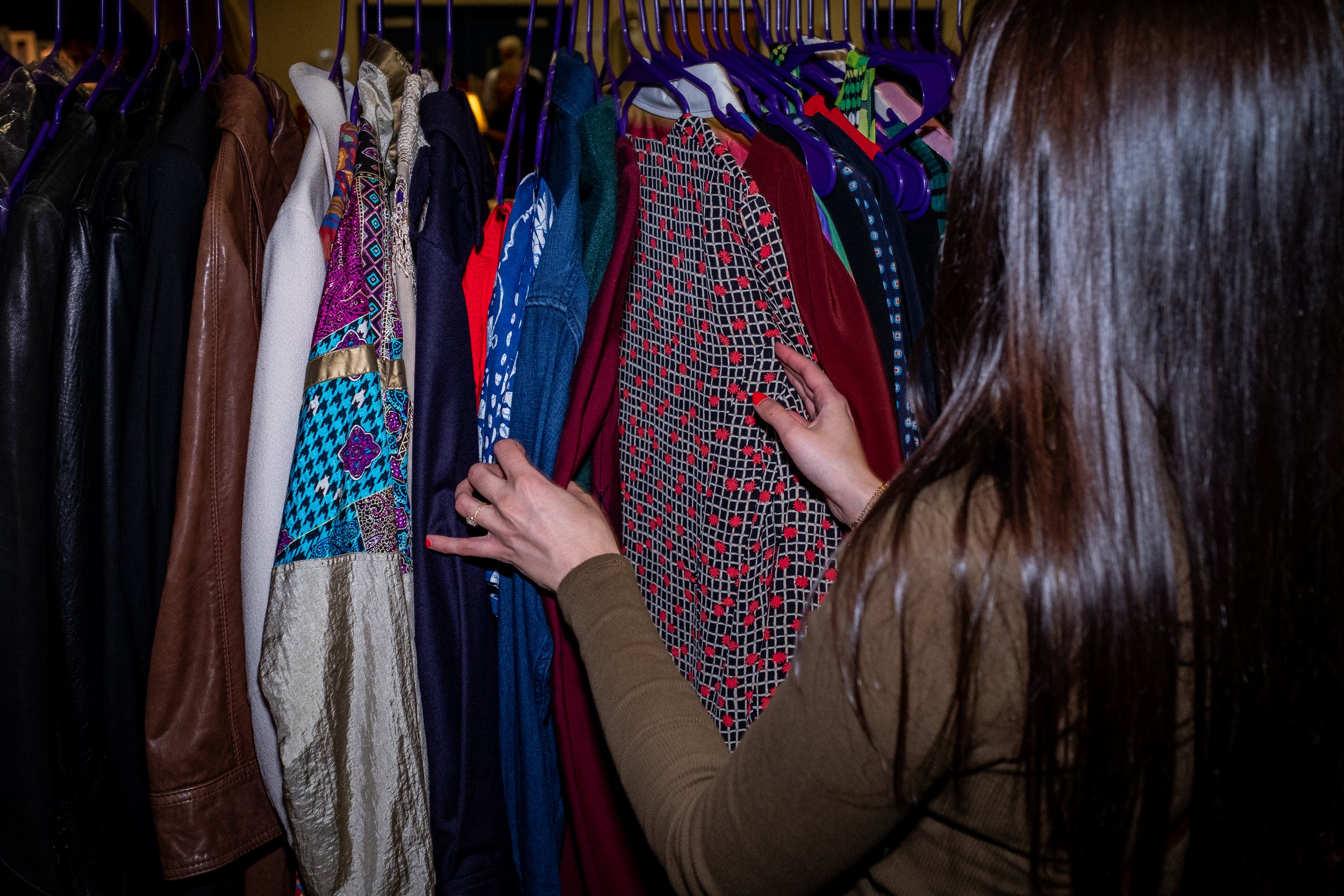 Woman browses through a rack of clothes.