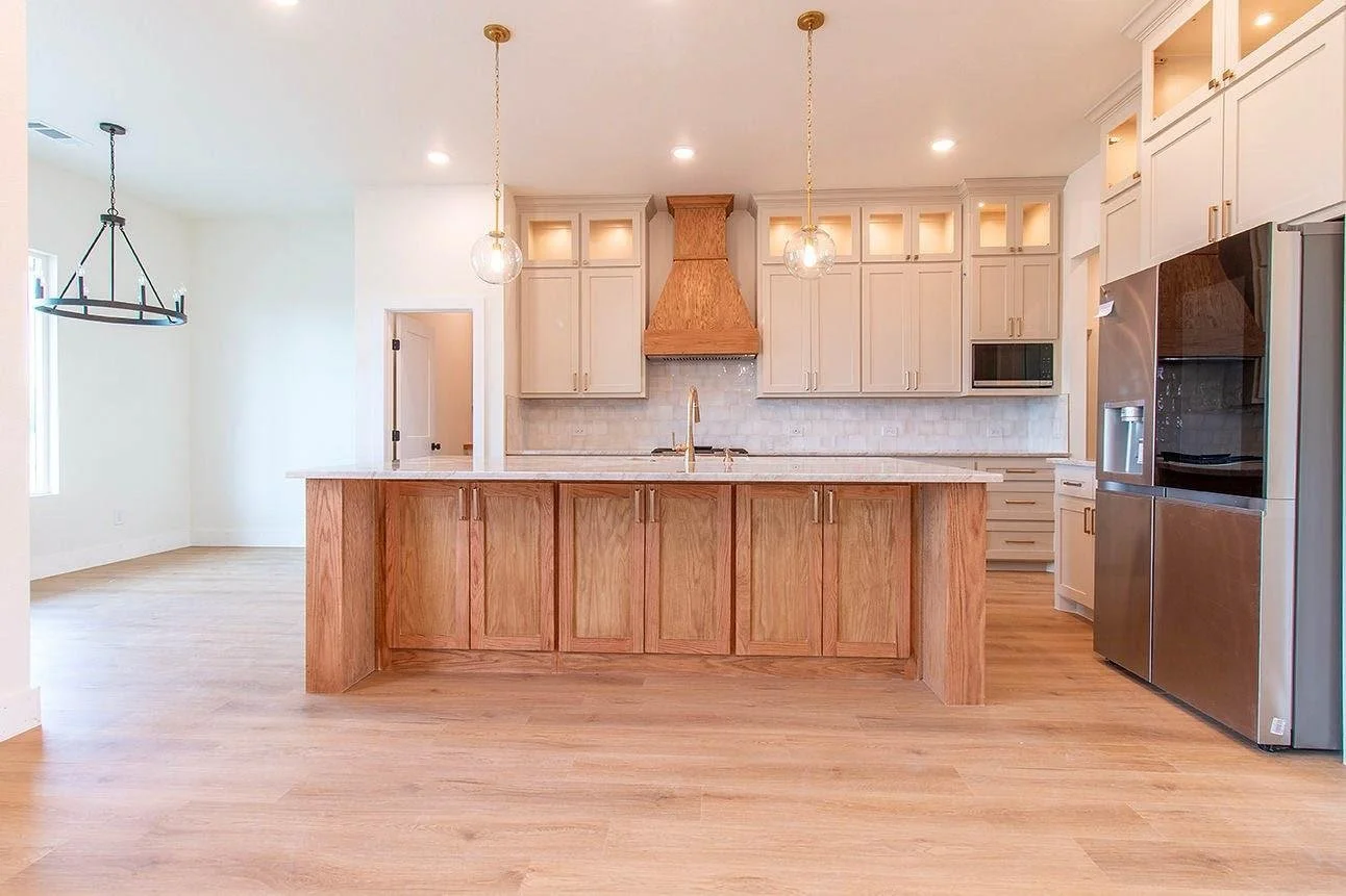 Modern kitchen with wooden island, white cabinets, stainless steel appliances, and pendant lighting.
