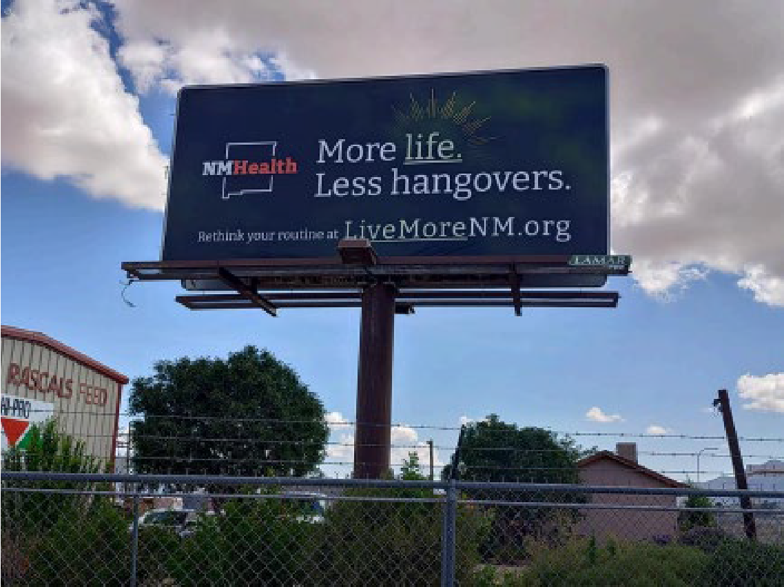 A billboard advertisement promoting healthier drinking habits with the message: "More life, Less hangovers" and a website link: LiveMoreNM.org.
