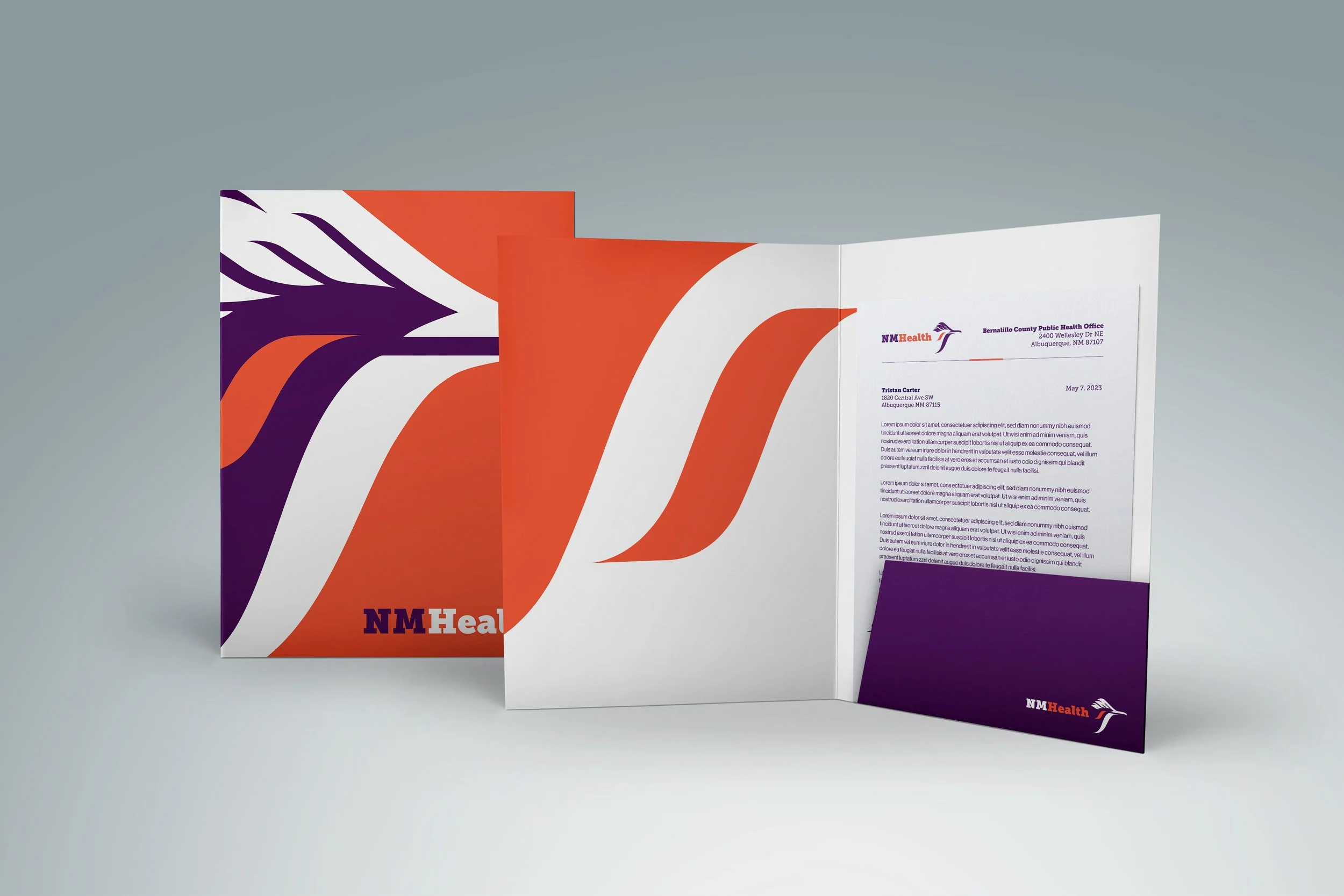 Open brochures with NMHealth branding, featuring abstract orange, purple, and white designs, and sample text visible on the inside page.