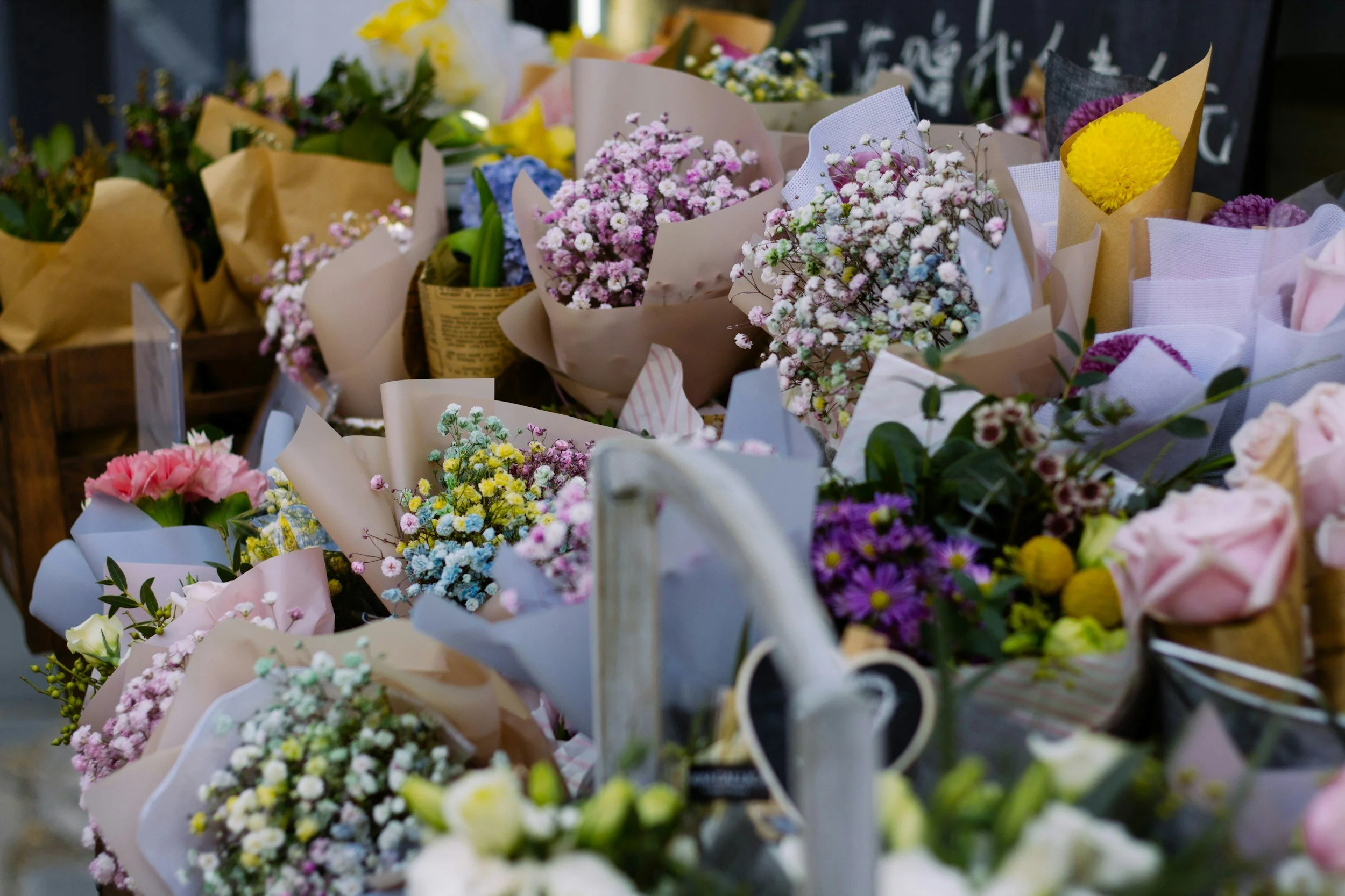 Various colorful flower bouquets wrapped in paper and placed in baskets on display in a flower shop.
