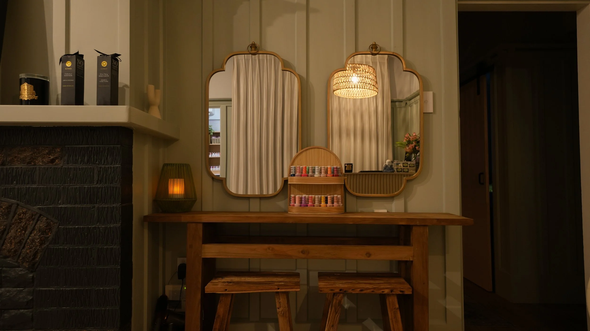 Interior of a room with three mirrors, a table with poker chips, and various decor items, including a lamp and a flower arrangement.